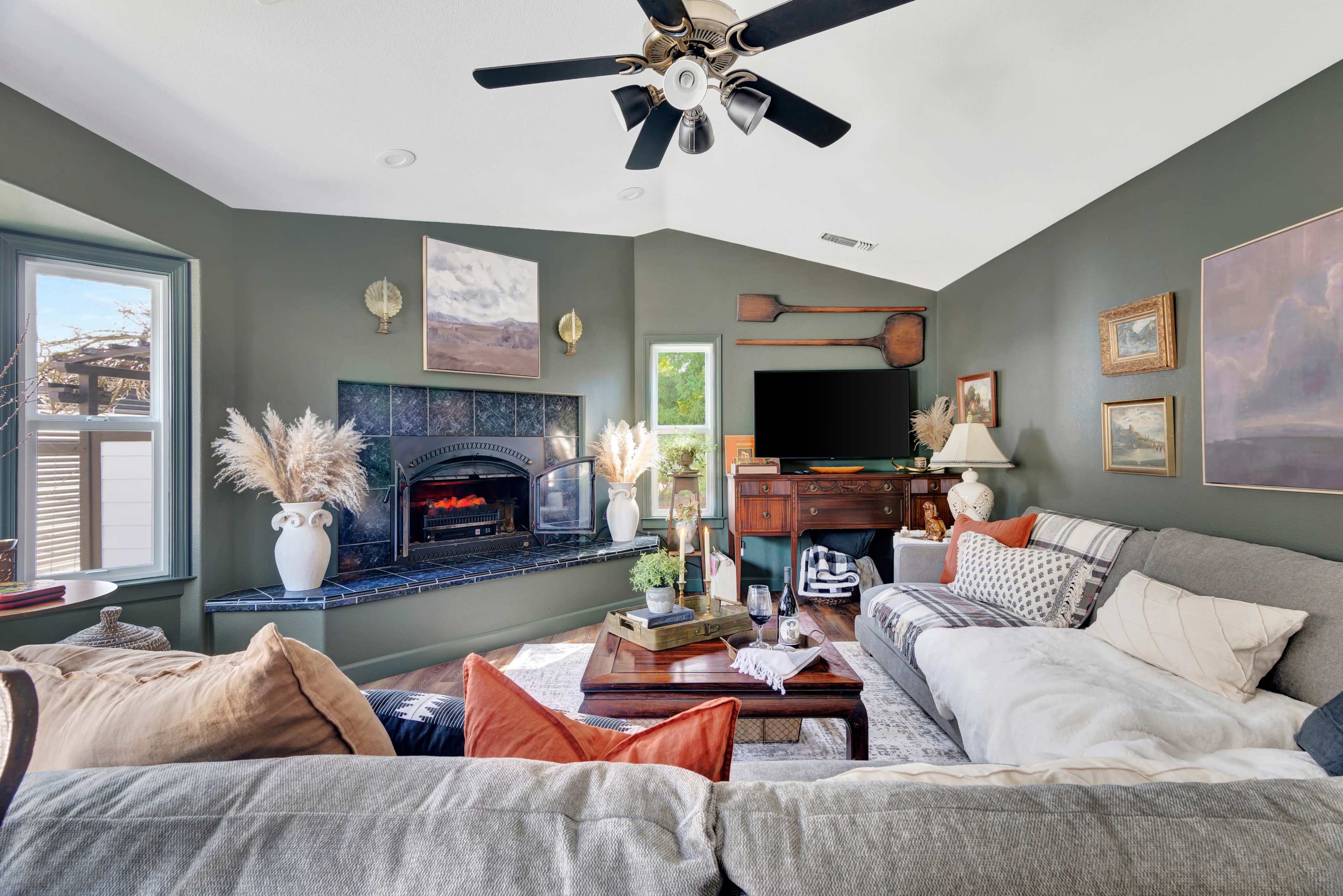 A cozy living room with a fireplace, a large sectional sofa, and decorative accents on the walls.