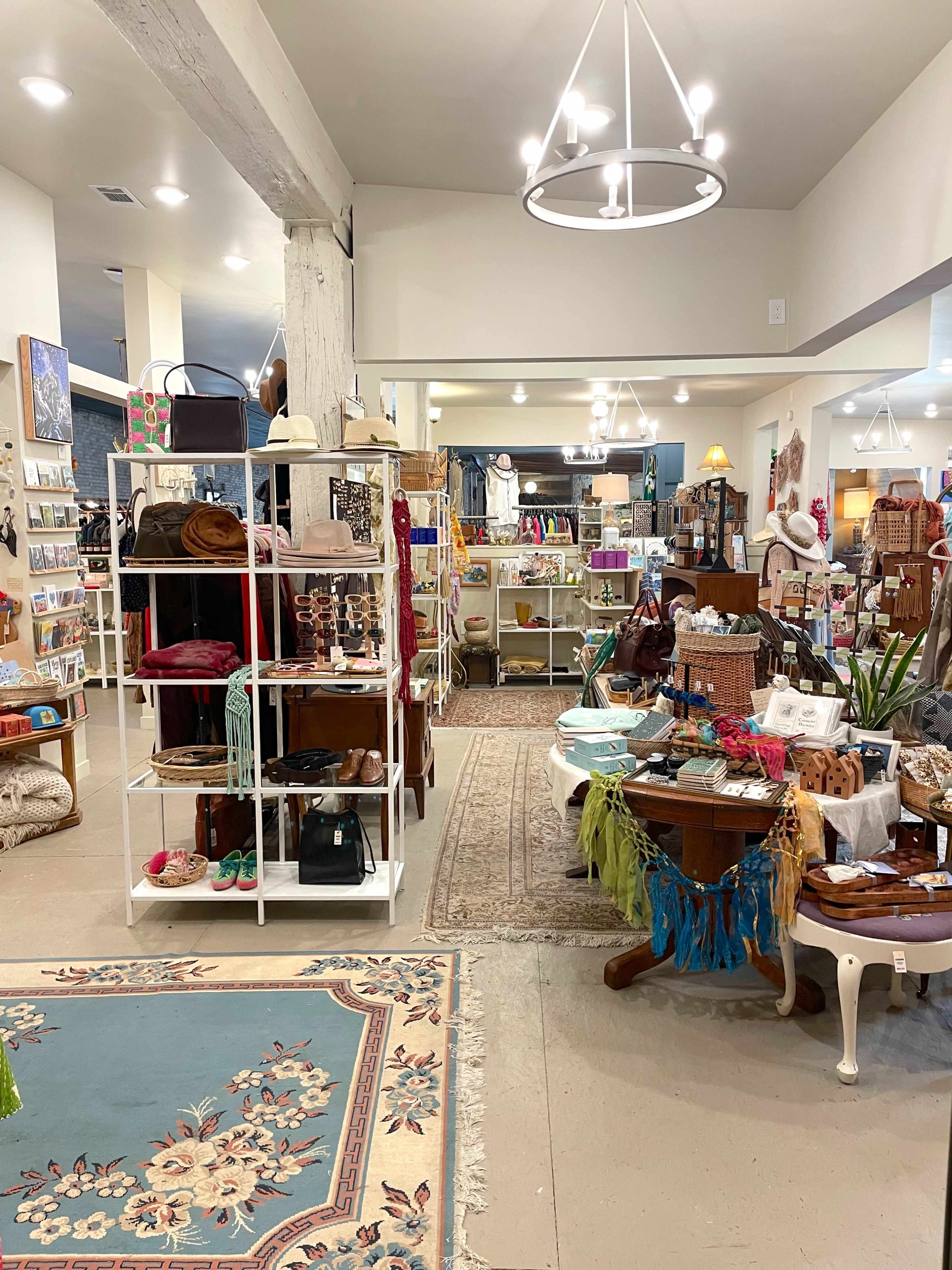 The image shows a boutique filled with various colorful merchandise, including clothing, accessories, and home decor, arranged on shelves and tables.