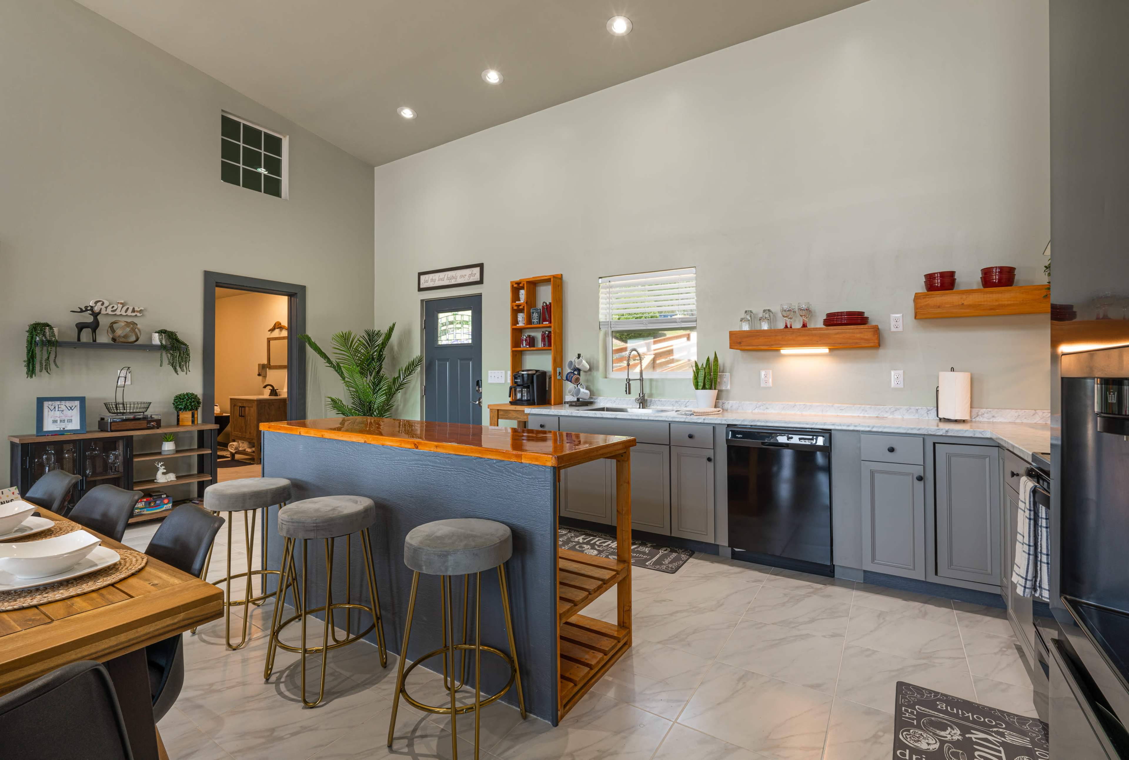 A modern kitchen with gray cabinetry, a large island with bar seating, and stainless steel appliances.