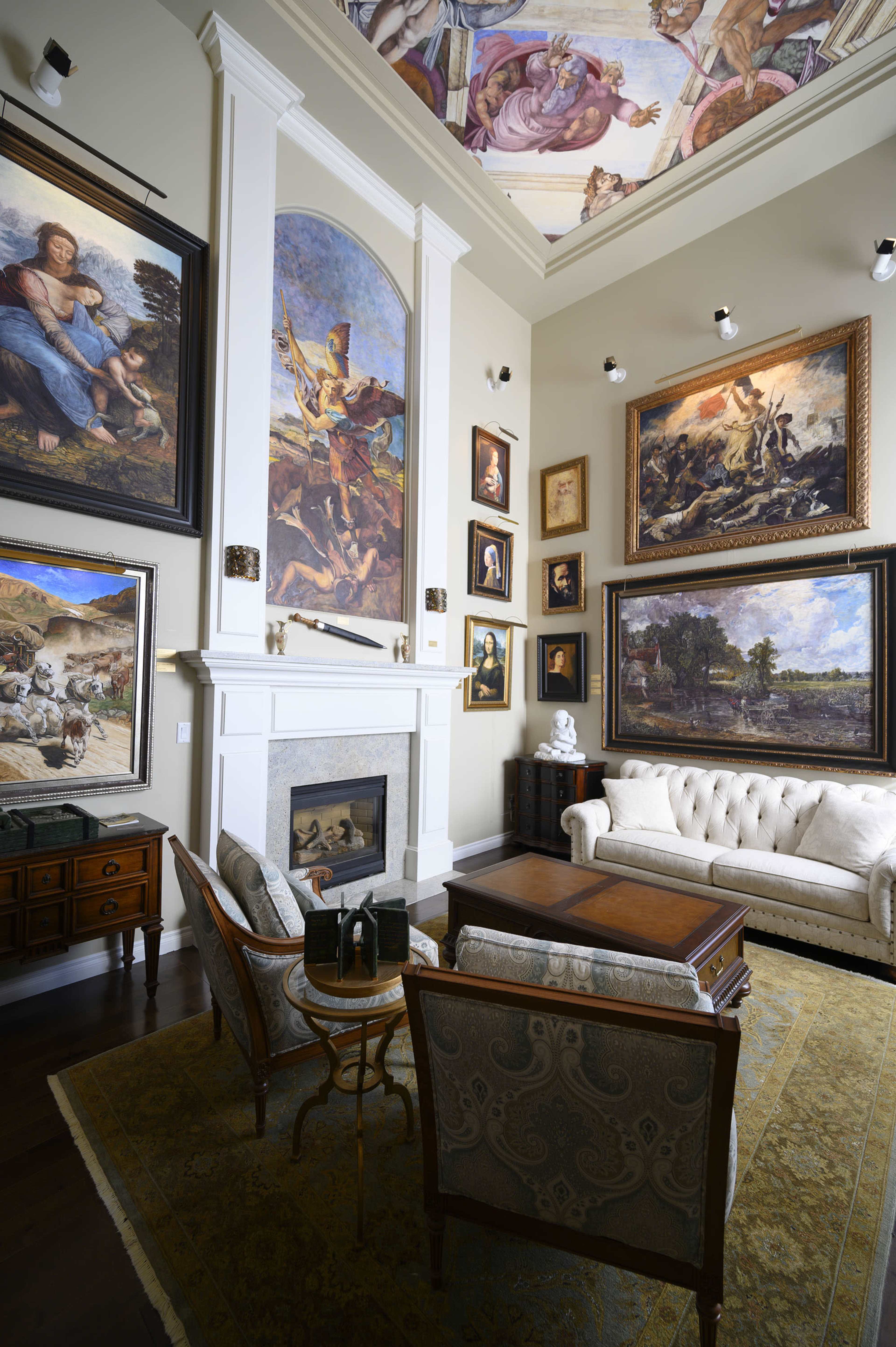 The room features a white couch, a wooden coffee table, and walls adorned with large framed paintings, including a mural on the ceiling.