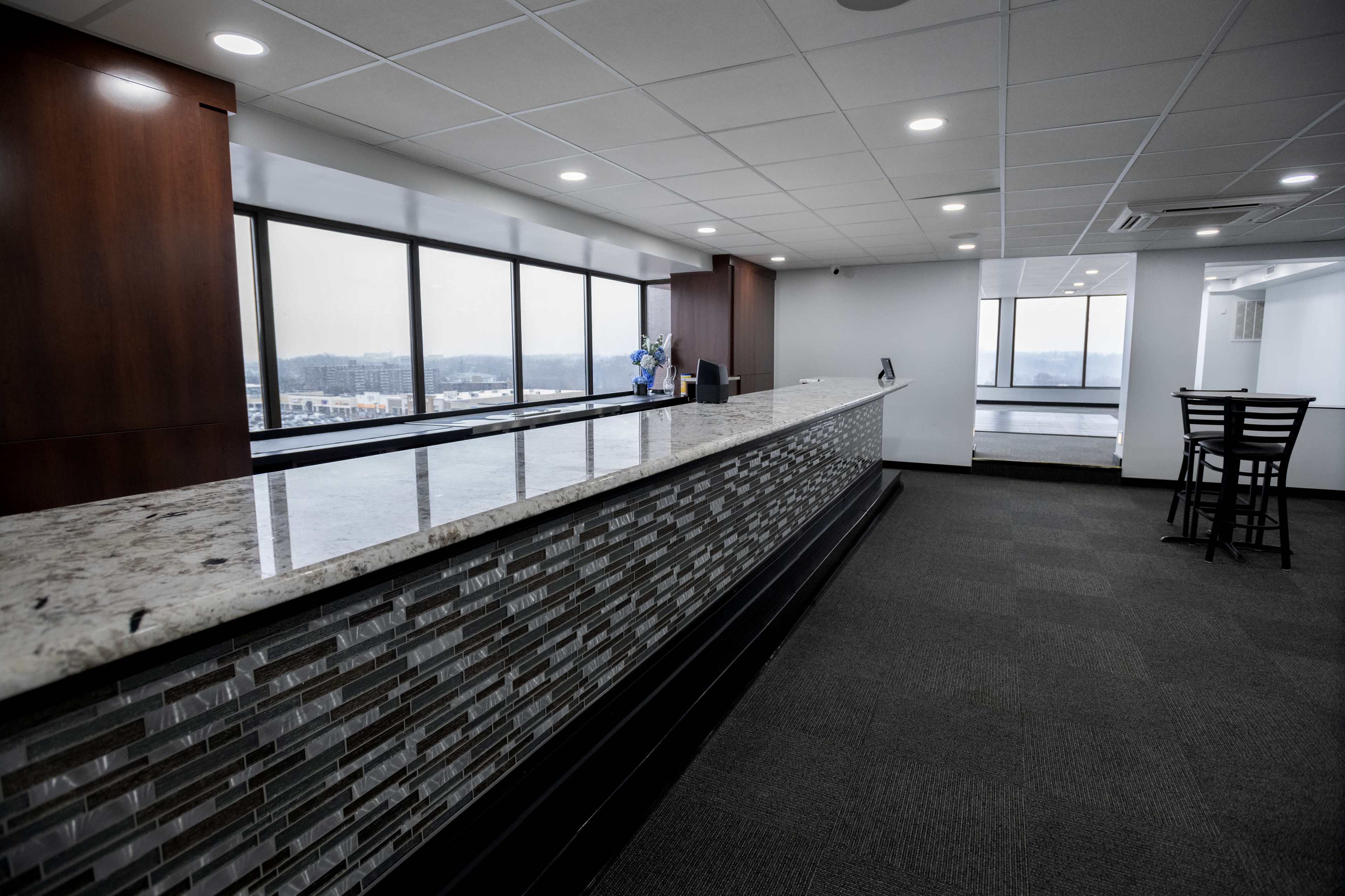 A modern reception area with a granite countertop and large windows providing a view of the outside.