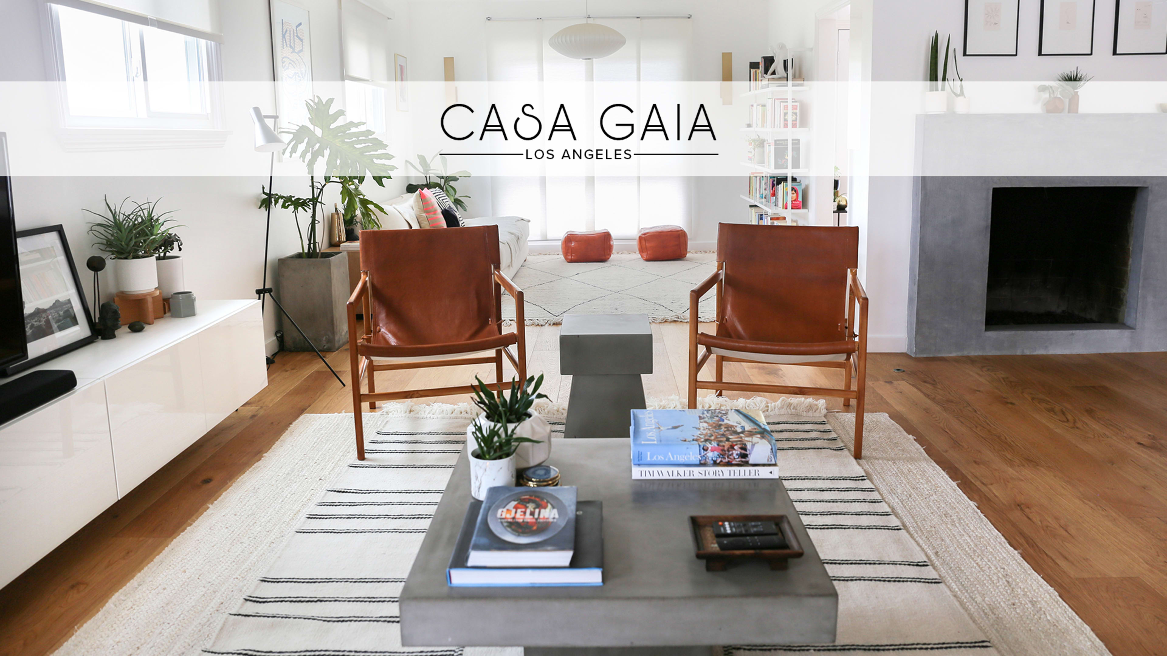 A modern living room featuring two leather chairs, a concrete coffee table, and light wood flooring with a rug.