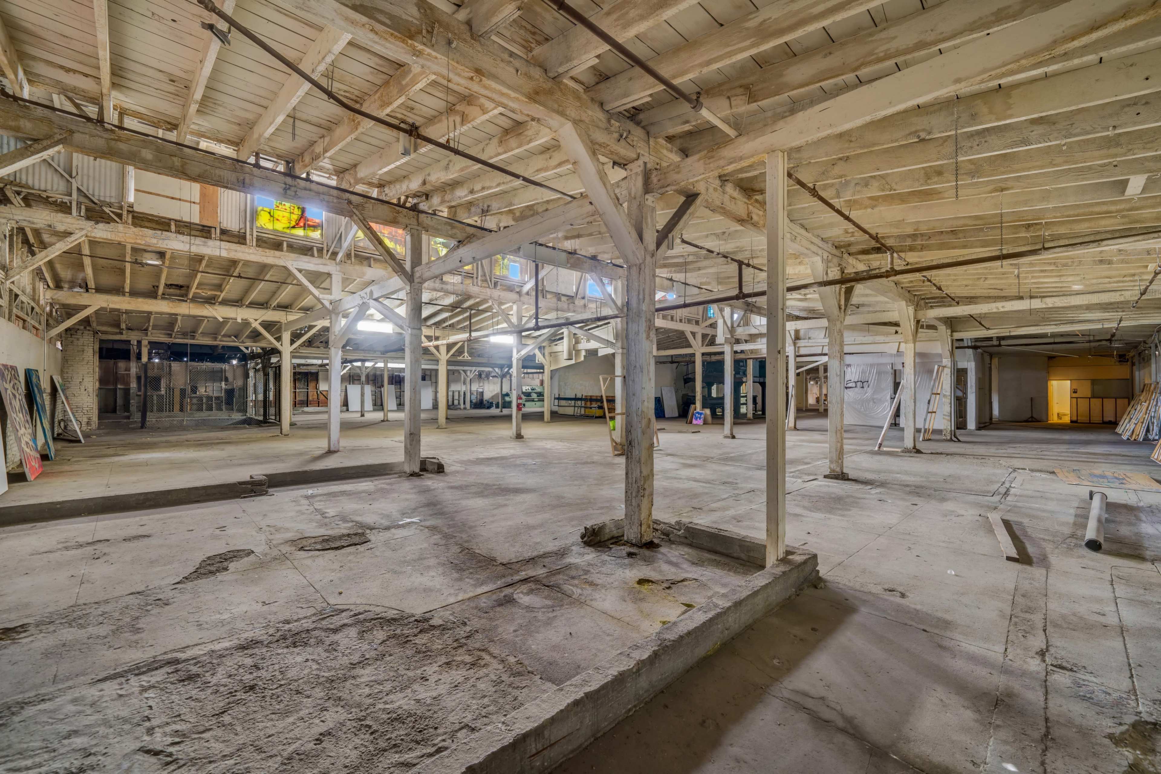 A large, empty industrial space with exposed wooden beams and concrete flooring.