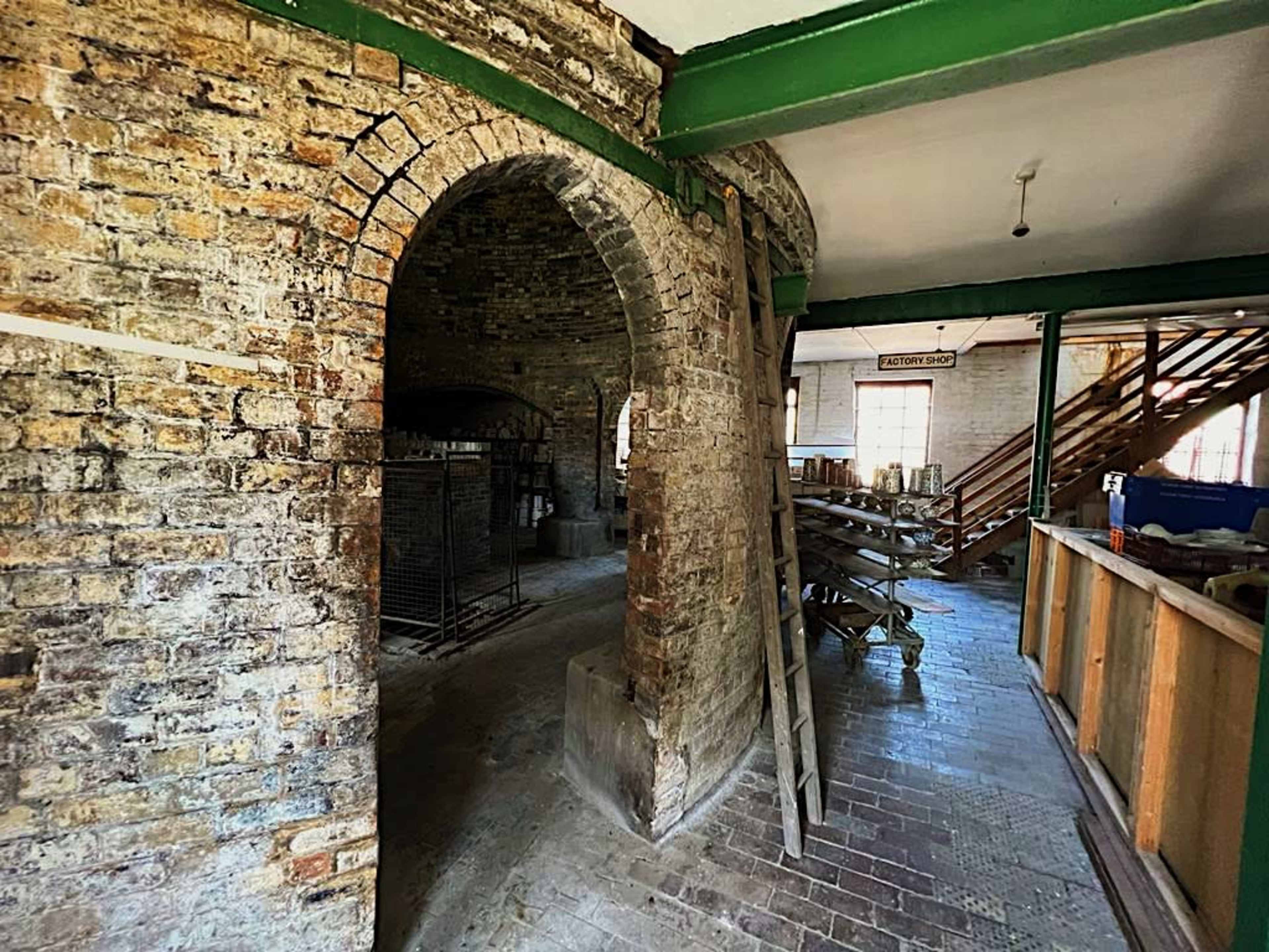 An interior space with exposed brick walls, arched doorways, and wooden scaffolding.