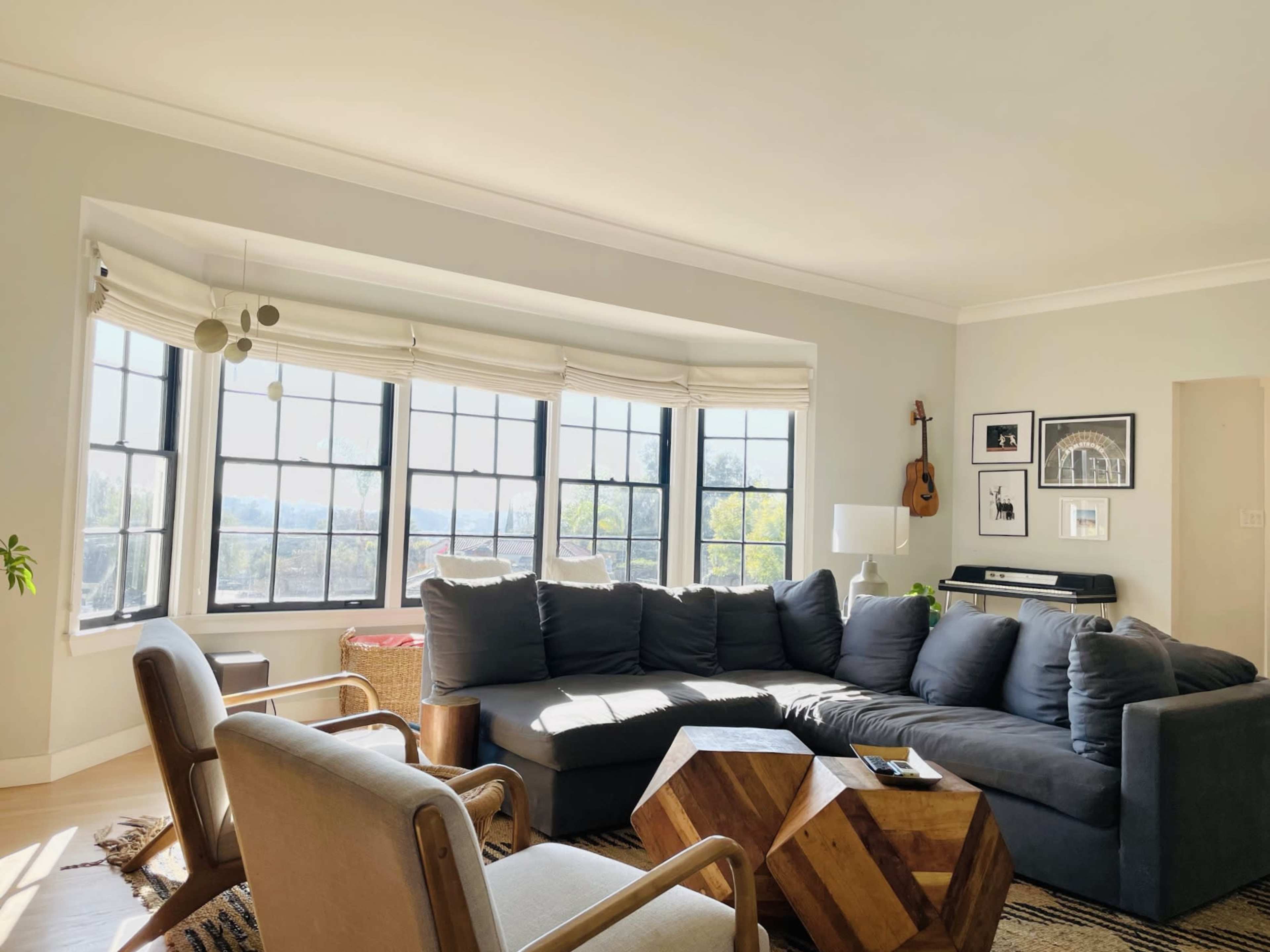 A spacious living room features a large sectional sofa, wooden coffee table, and large windows with a view.