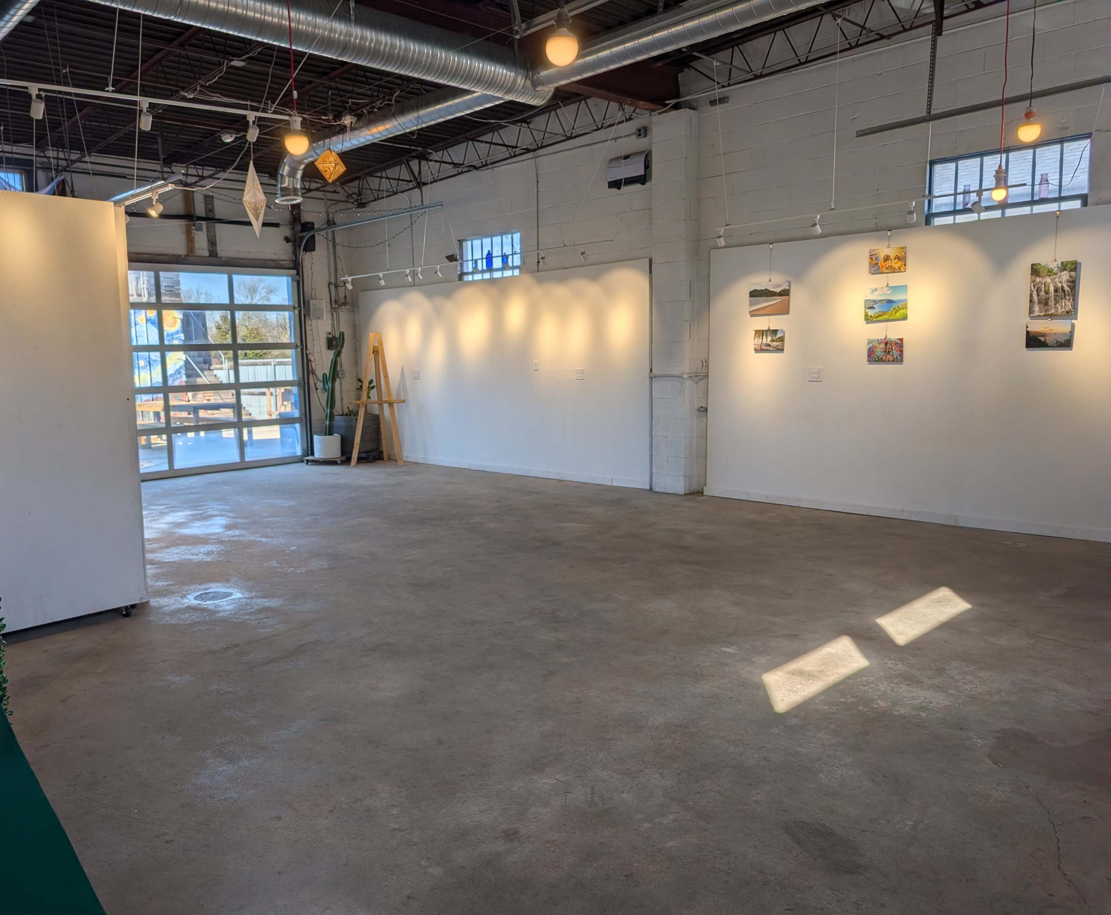 The image shows a spacious, well-lit art gallery with white walls displaying several framed photographs.