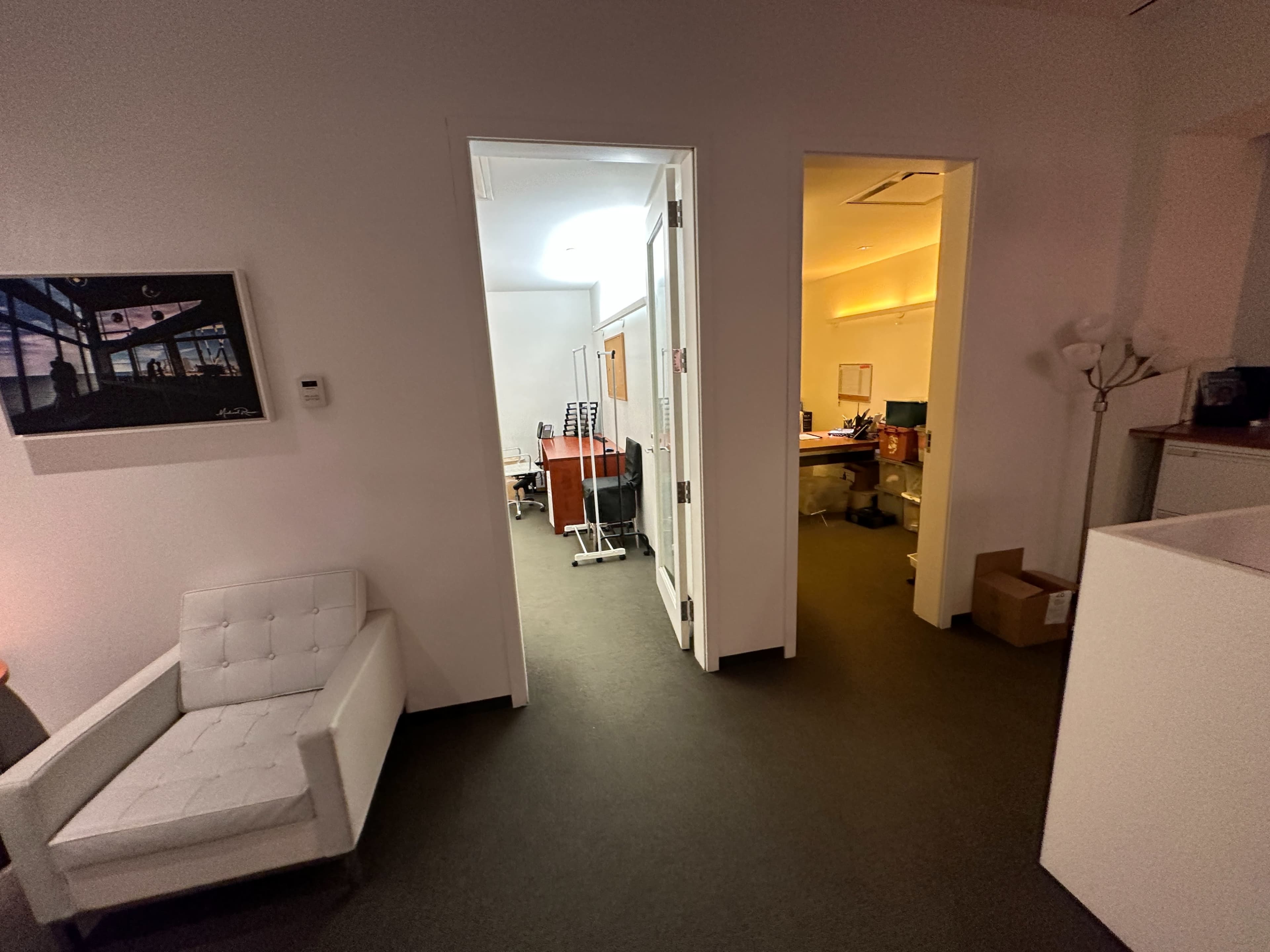 A modern office layout with a white chair in the foreground and two doorways leading to separate rooms in the background.