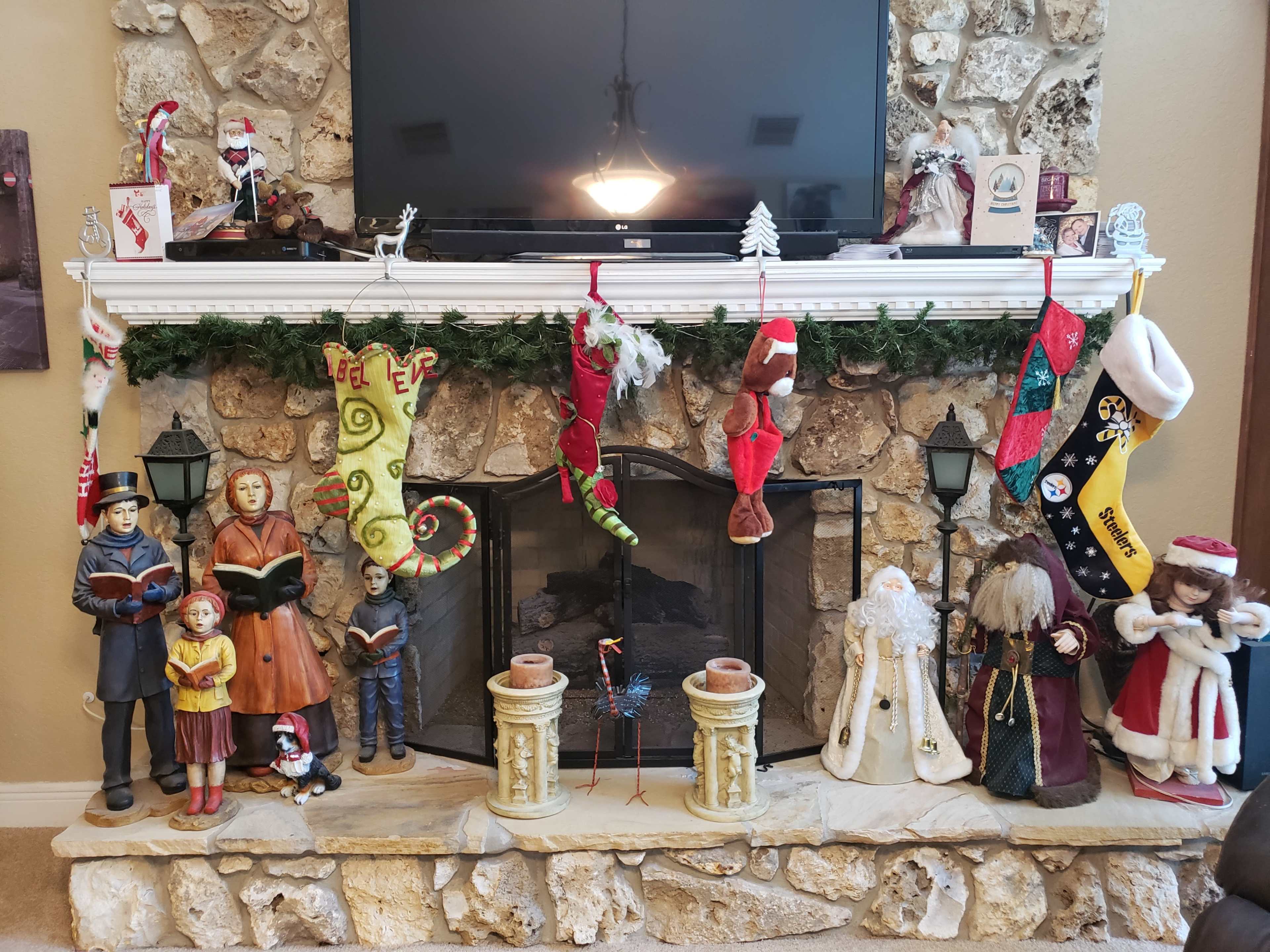 A decorated fireplace mantel with various stockings, festive figures, and holiday decorations.