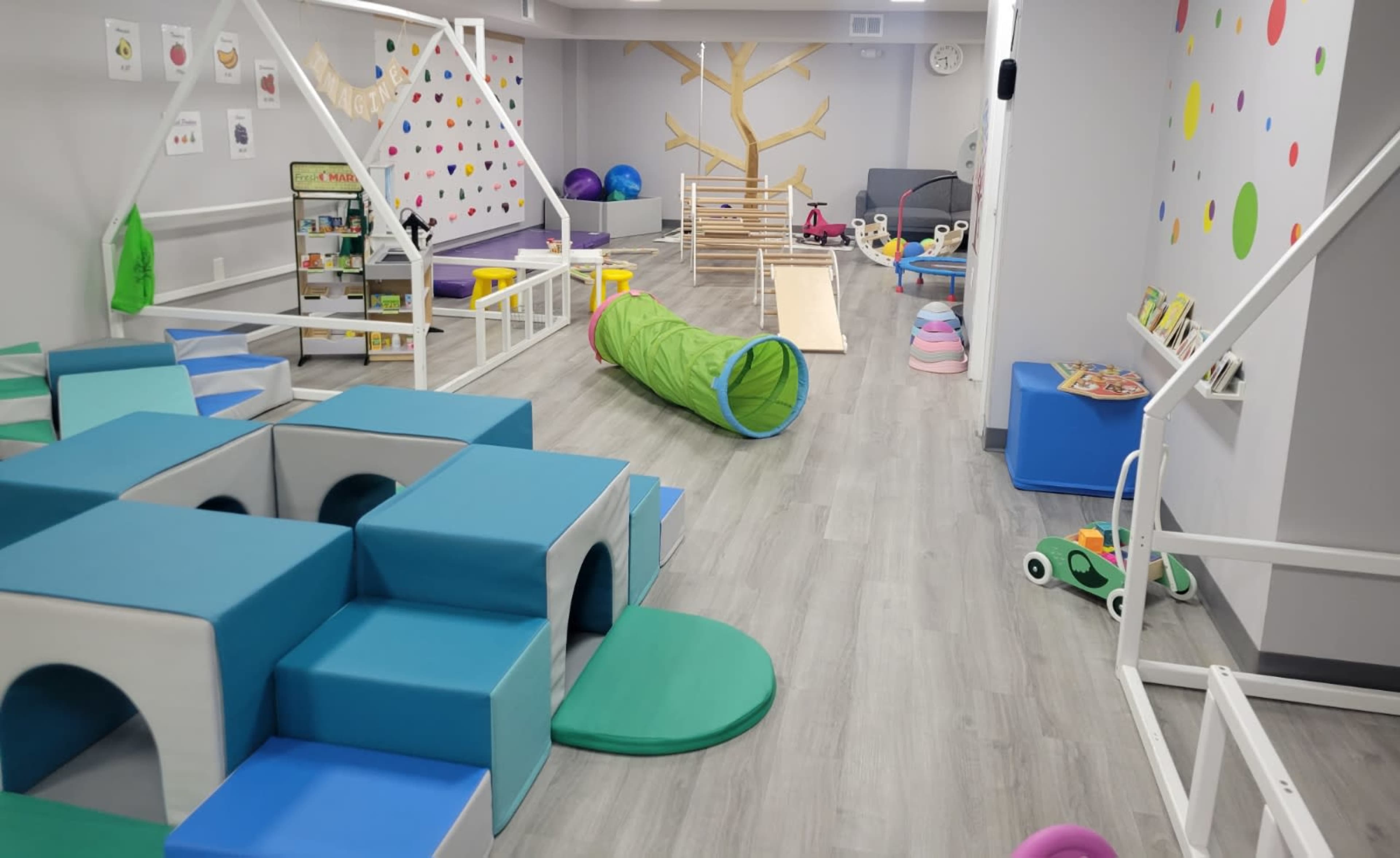 A colorful indoor play area designed for children, featuring various play structures, soft blocks, a tunnel, and a slide.