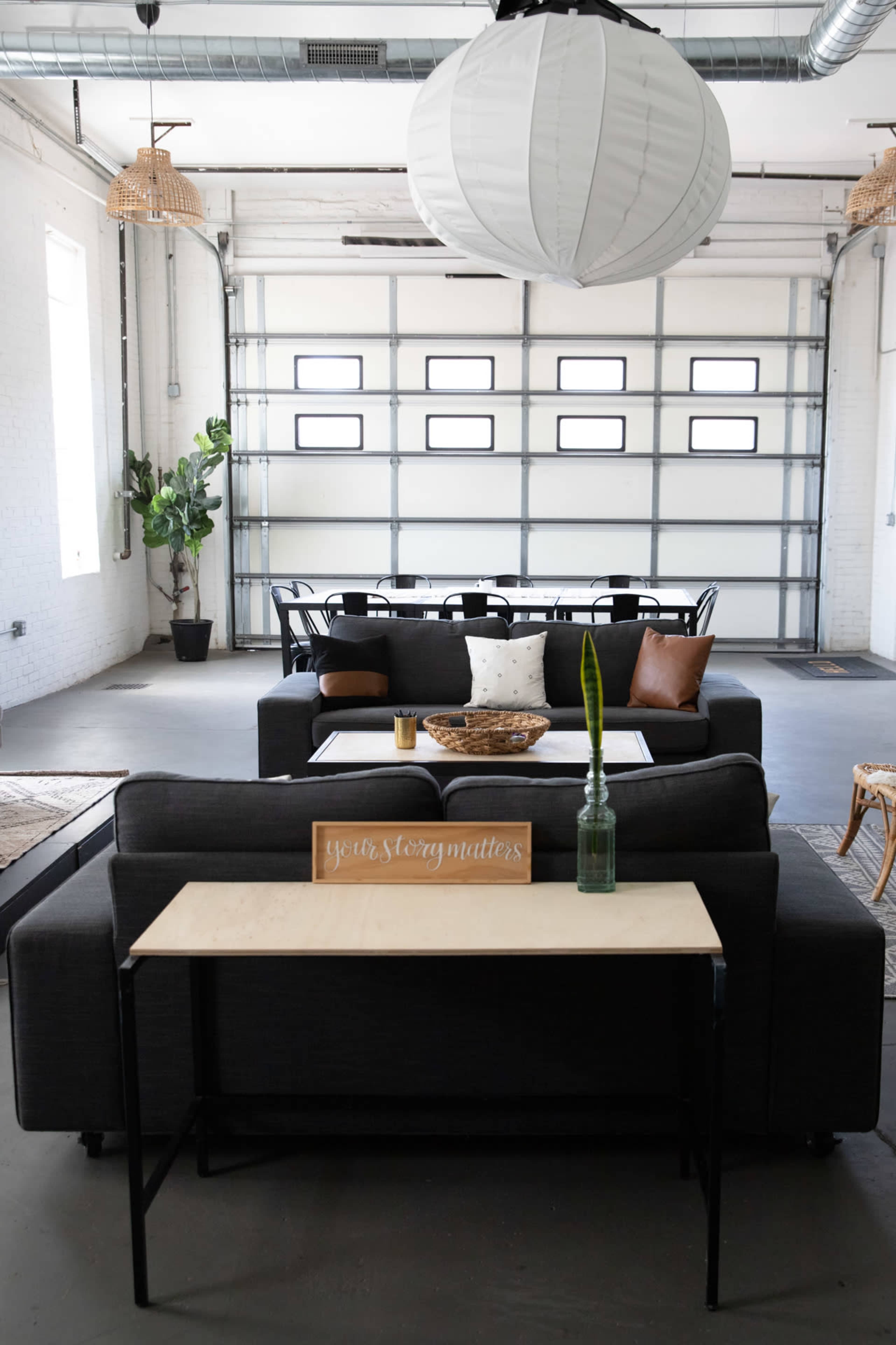 A modern living space with gray sofas, a wooden coffee table, and a large garage door in the background.