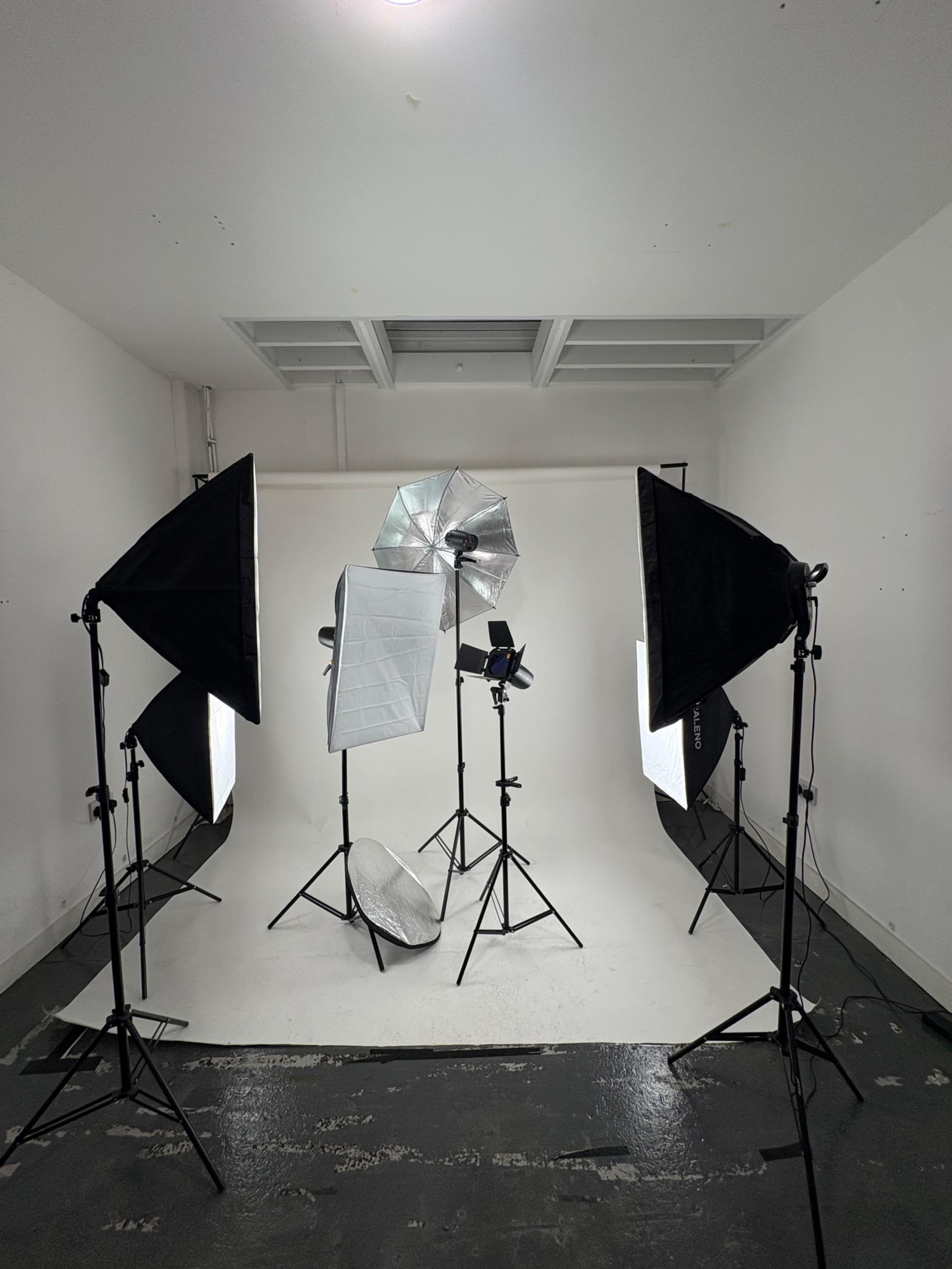 A photography studio setup features multiple softboxes and light stands arranged in front of a white backdrop.
