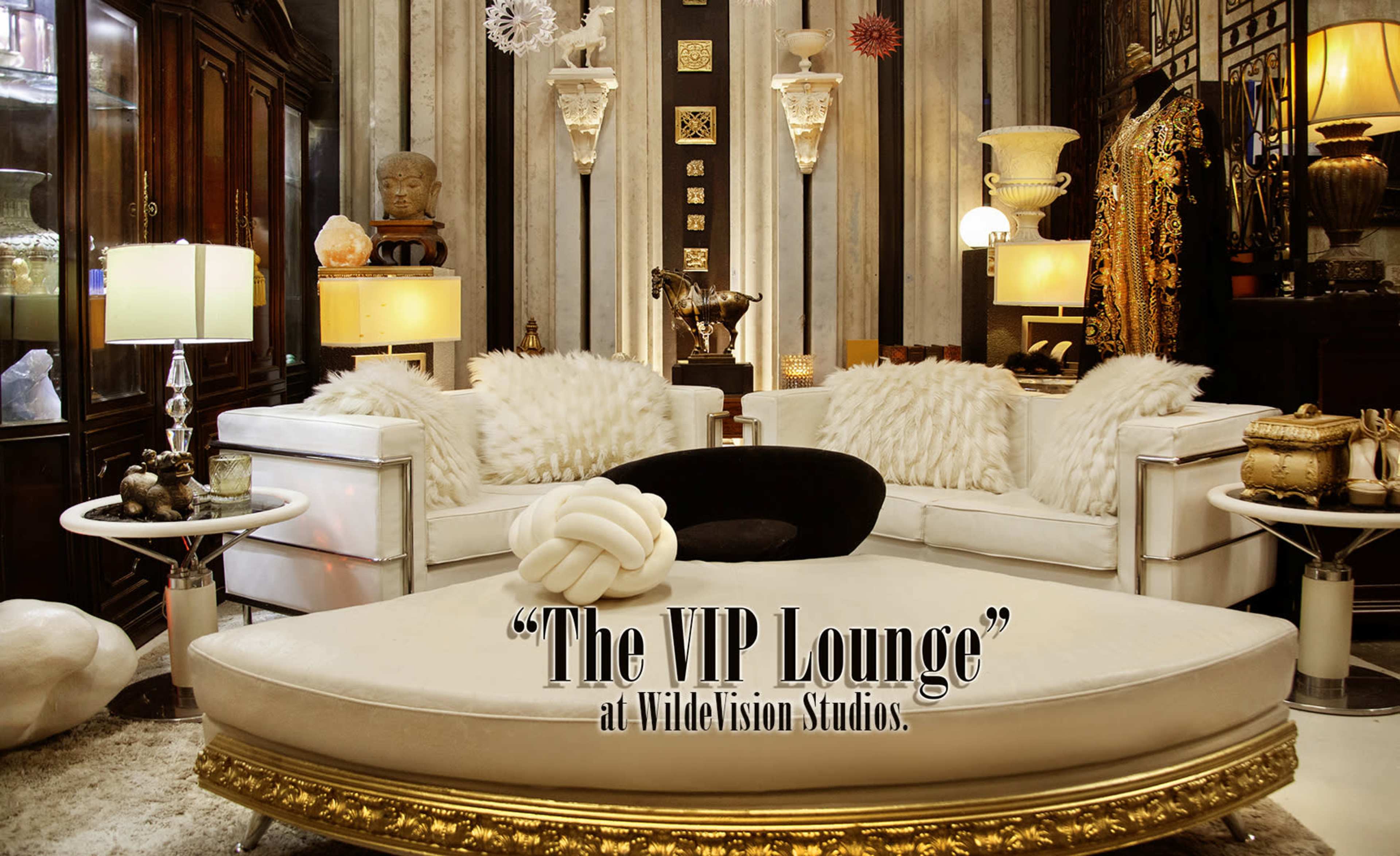 The image features an elegantly decorated lounge area with plush seating, ornate decor, and various artistic elements.
