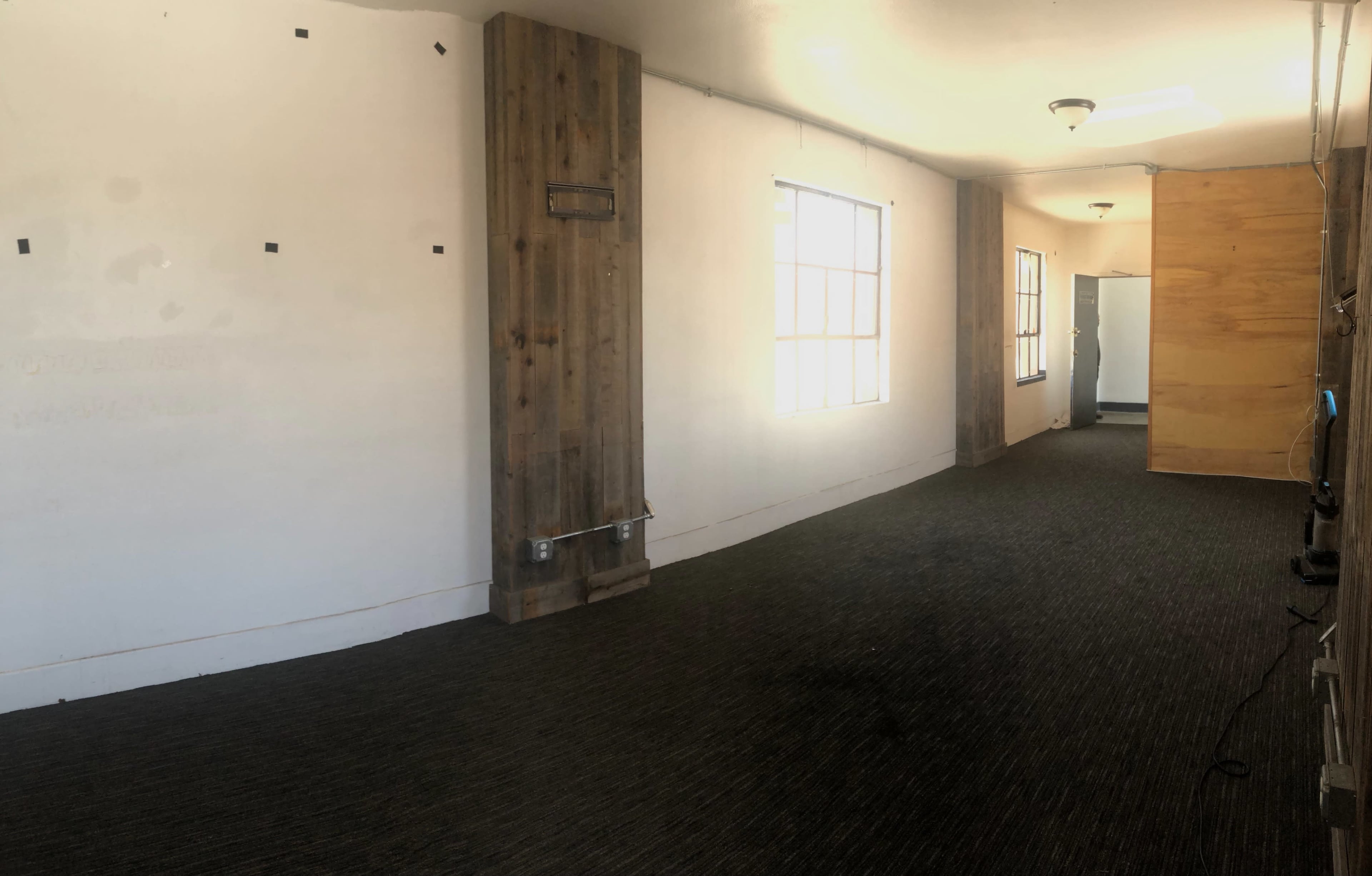 A long, empty hallway features white walls, wood paneling, and several light fixtures.