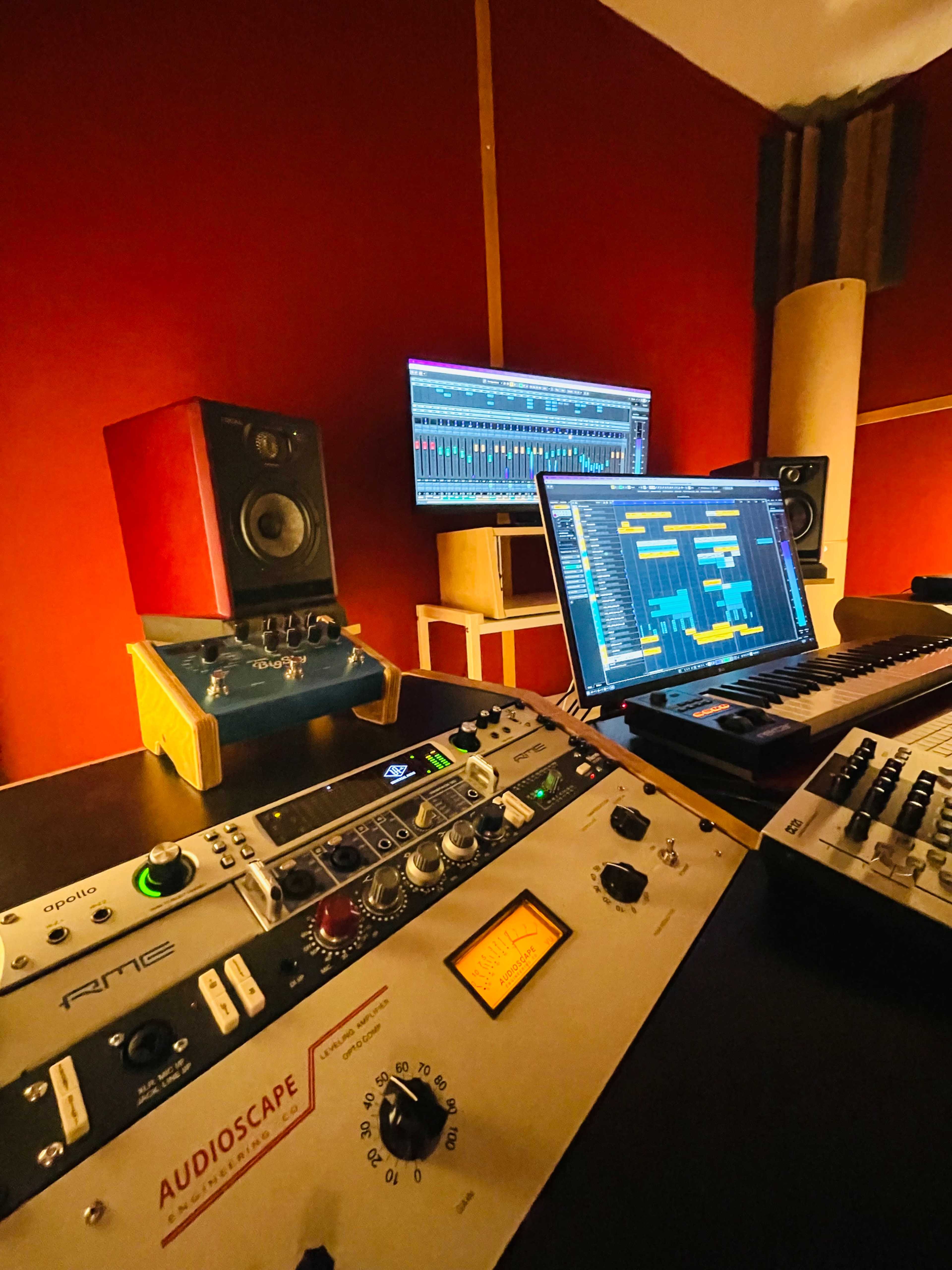 A recording studio setup with audio equipment, including speakers, a computer monitor displaying software, and a mixing console.