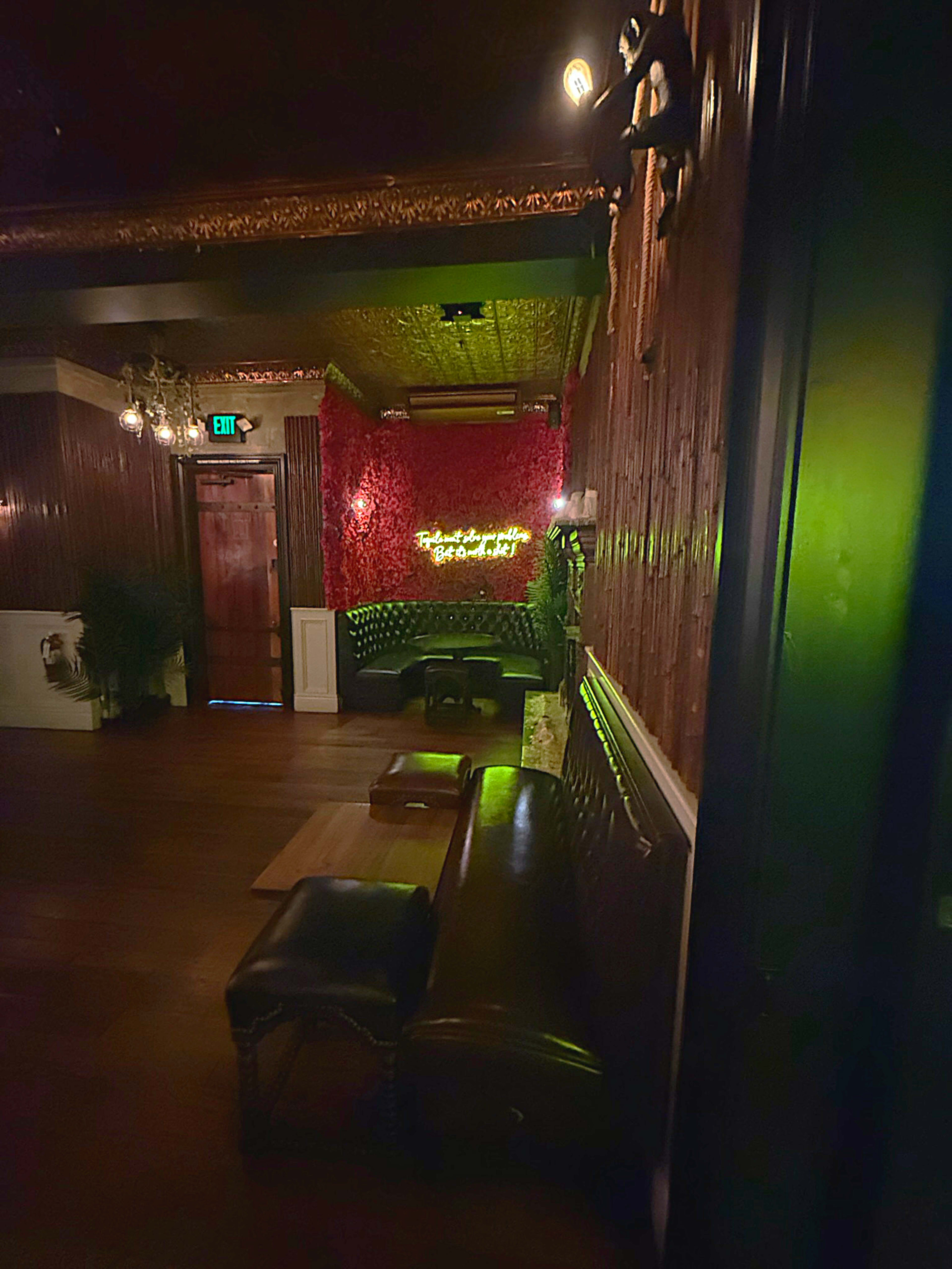The image shows the interior of a dimly lit lounge featuring leather seating and a decorative wall with what appears to be illuminated text.