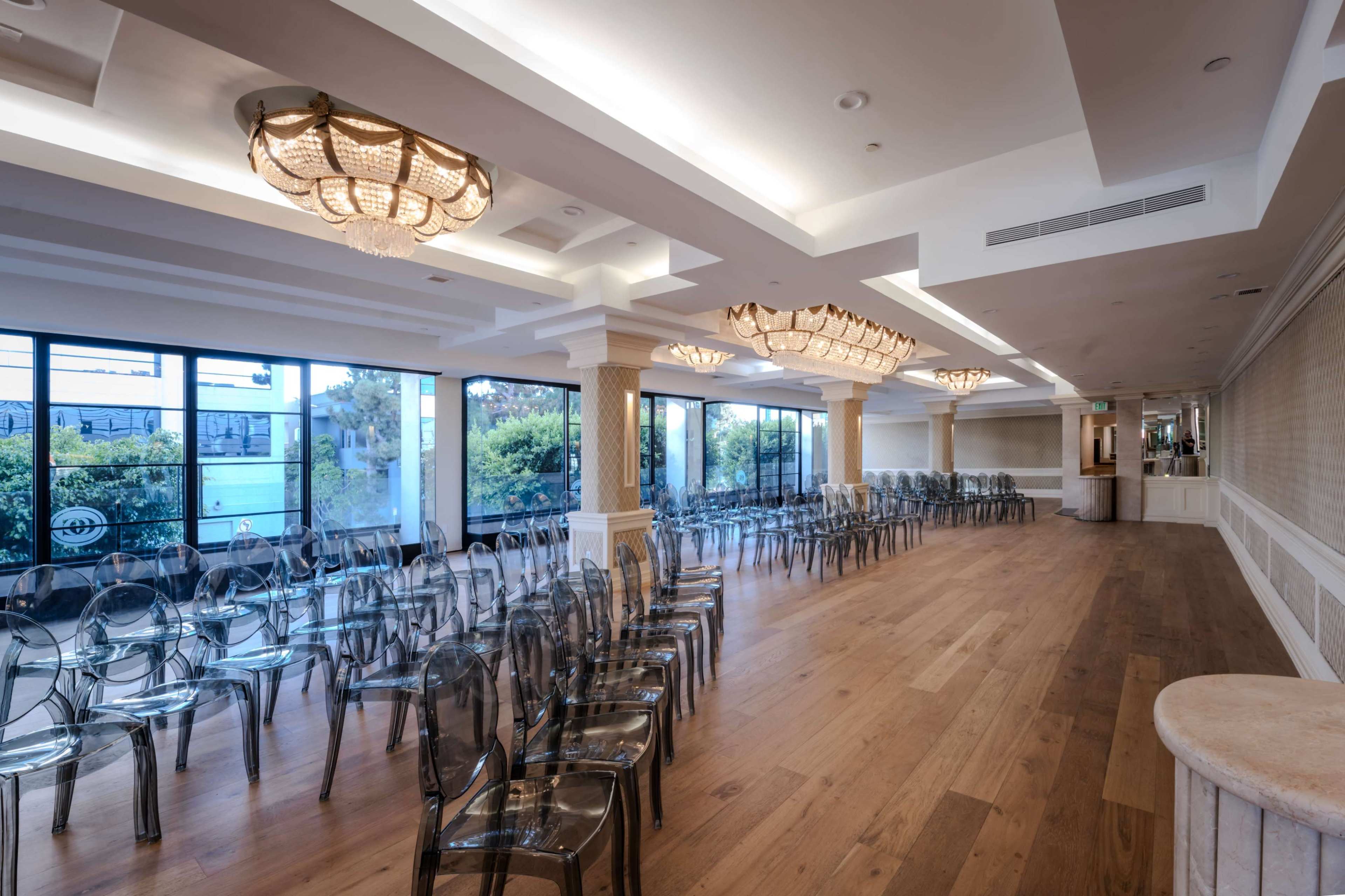 The image shows a spacious event room with clear acrylic chairs arranged in rows facing large windows.