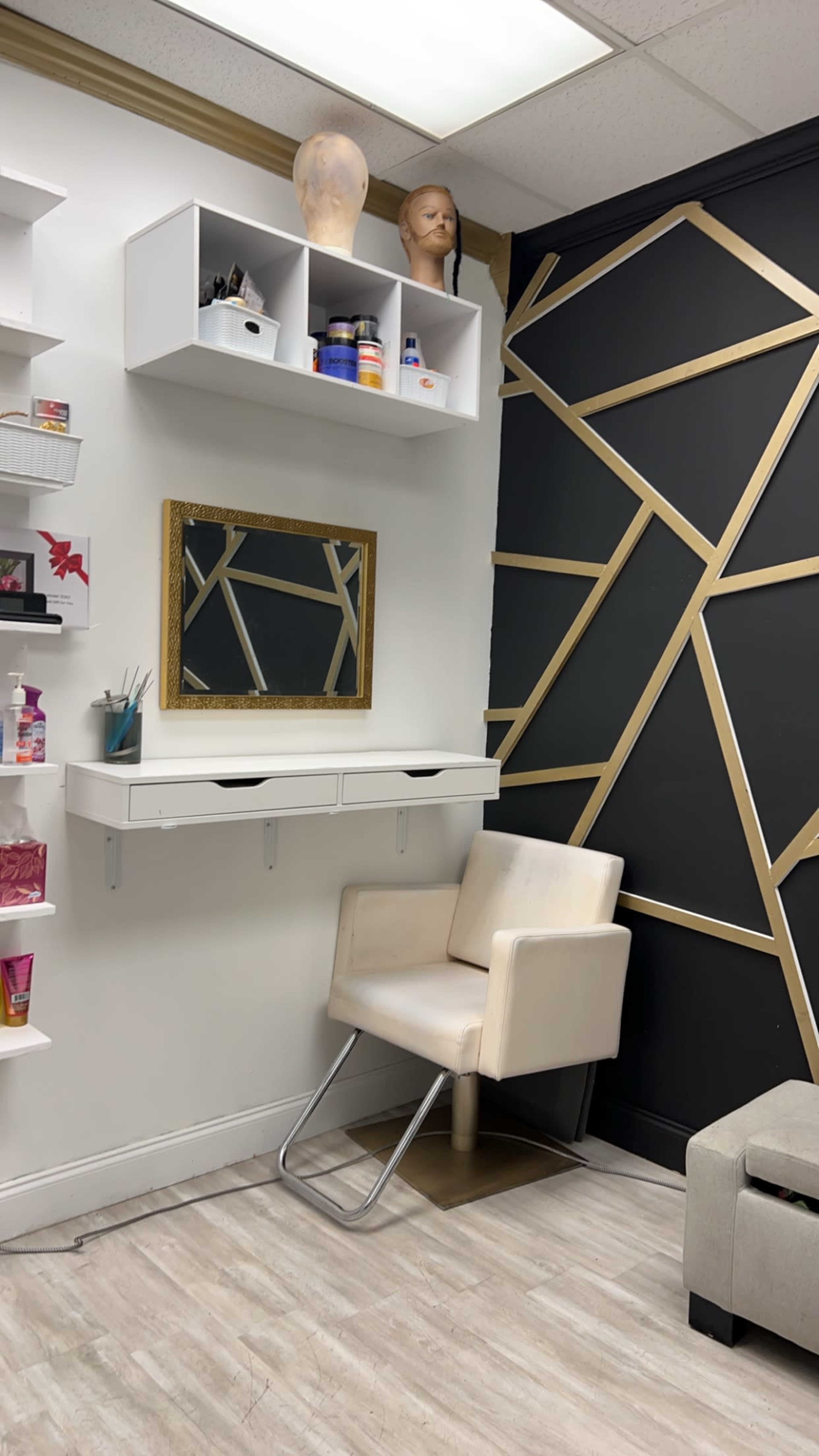 A corner of a salon with a chair, a mirror in a gold frame, and shelves containing various hair and beauty products.