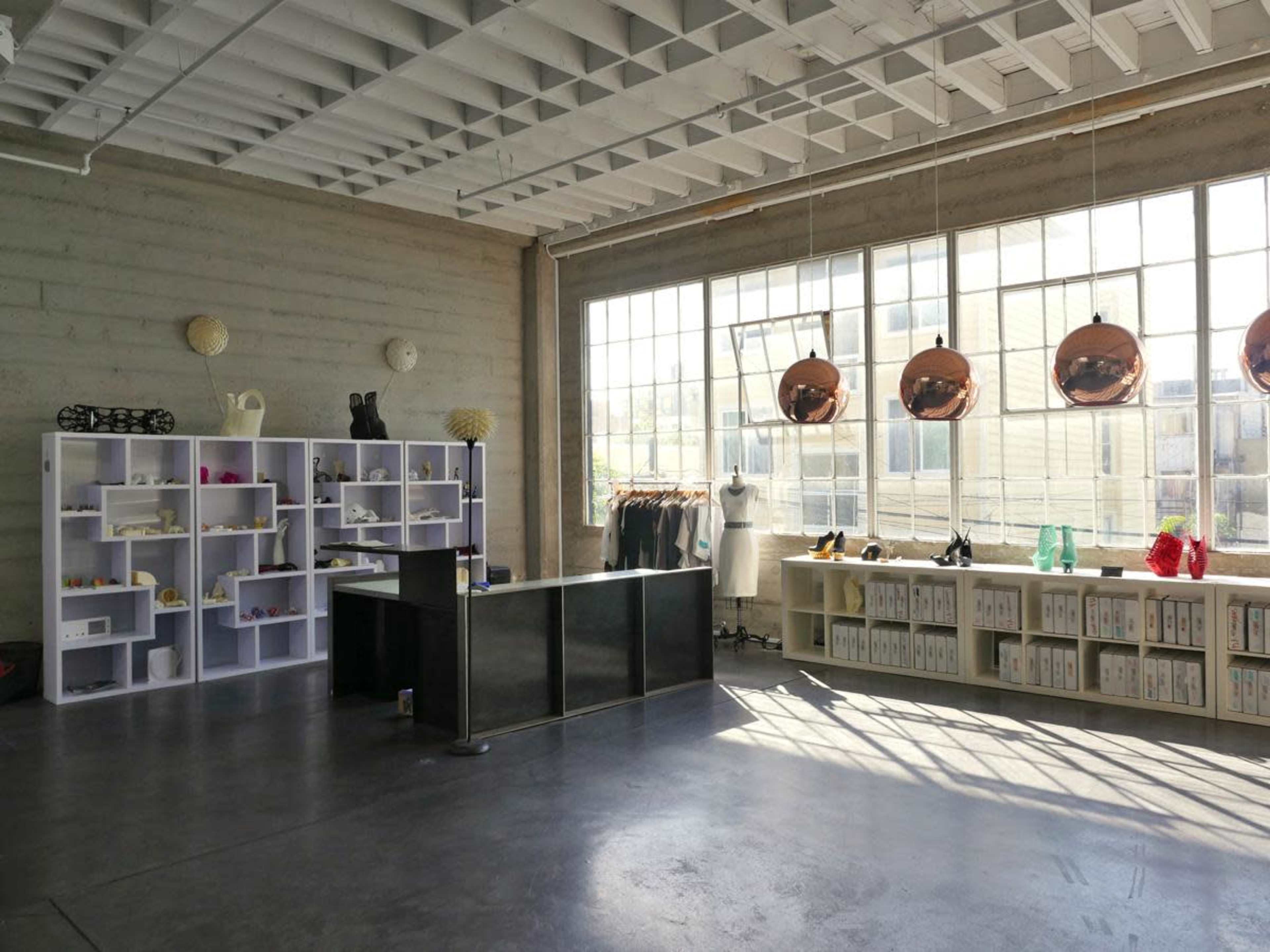 A spacious retail space with modern furnishings, including shelves, a reception desk, and large windows allowing natural light to enter.