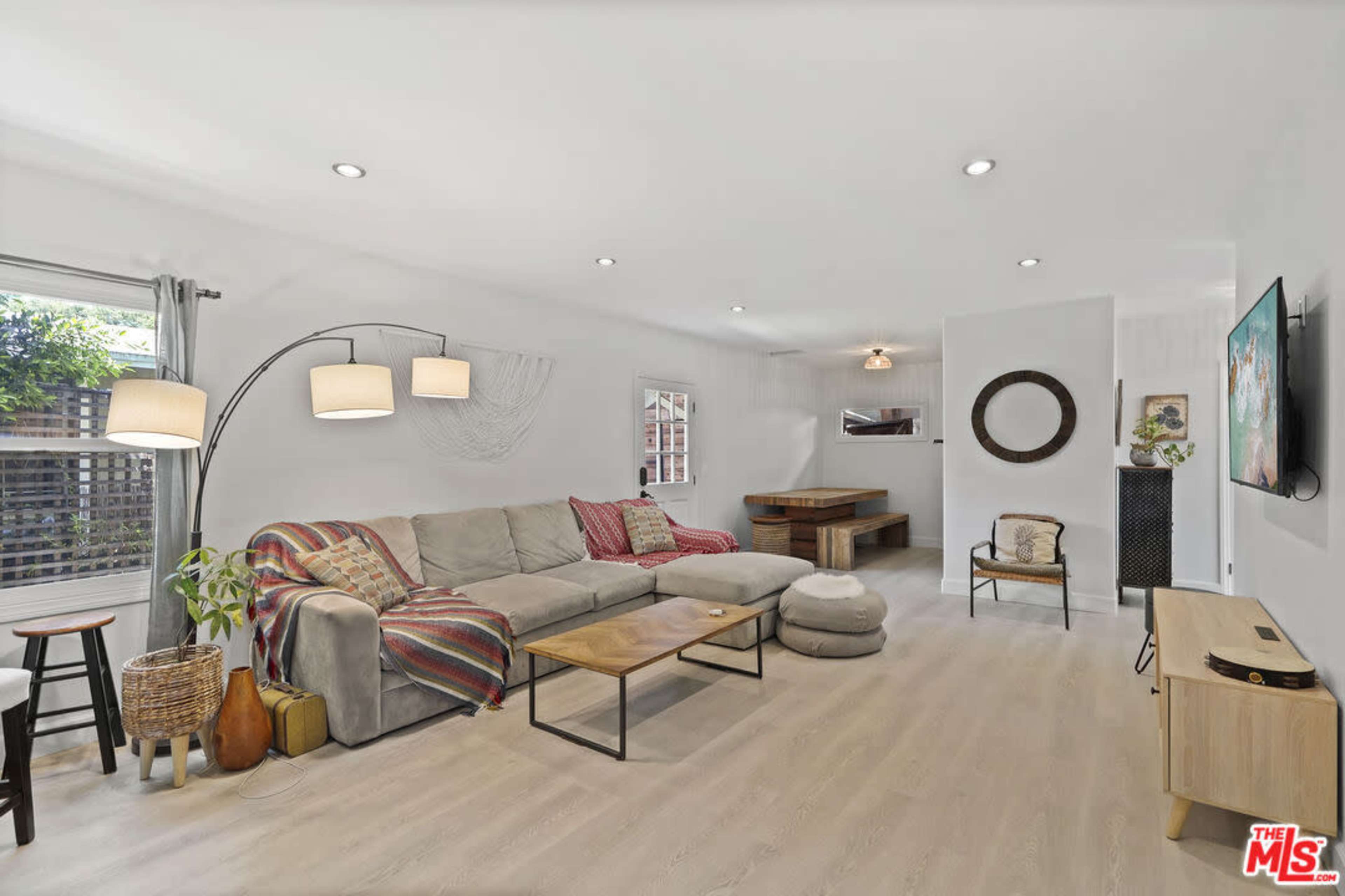 A bright living room with a large sofa, a coffee table, and a dining area in the background.