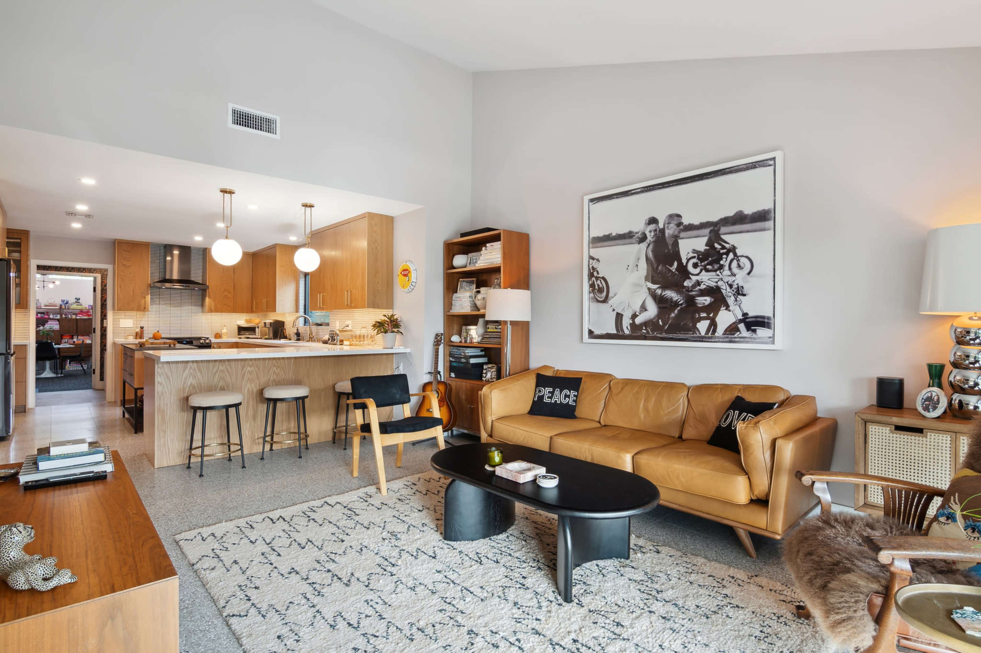 The living room features a leather sofa, a coffee table, and a kitchen area in an open-concept layout.