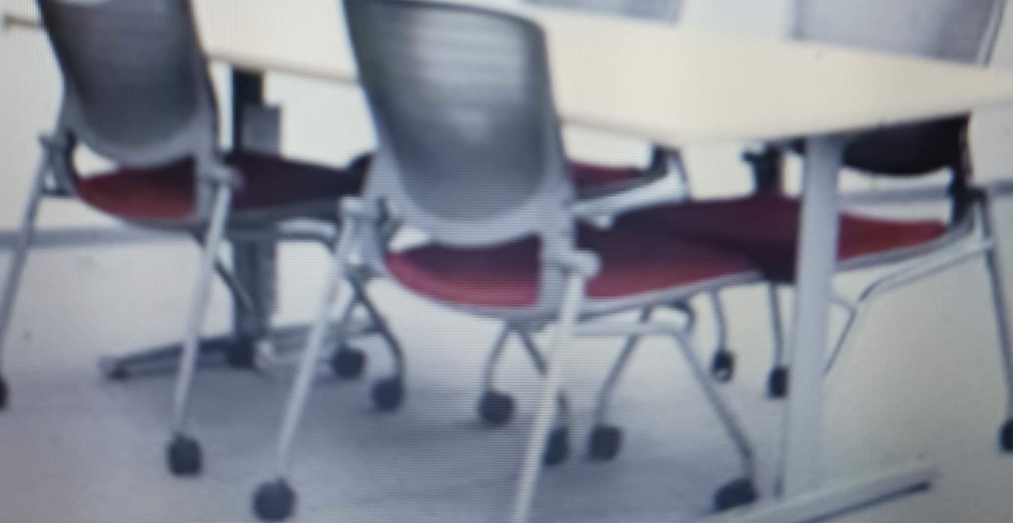 A set of four office chairs arranged around a rectangular table.