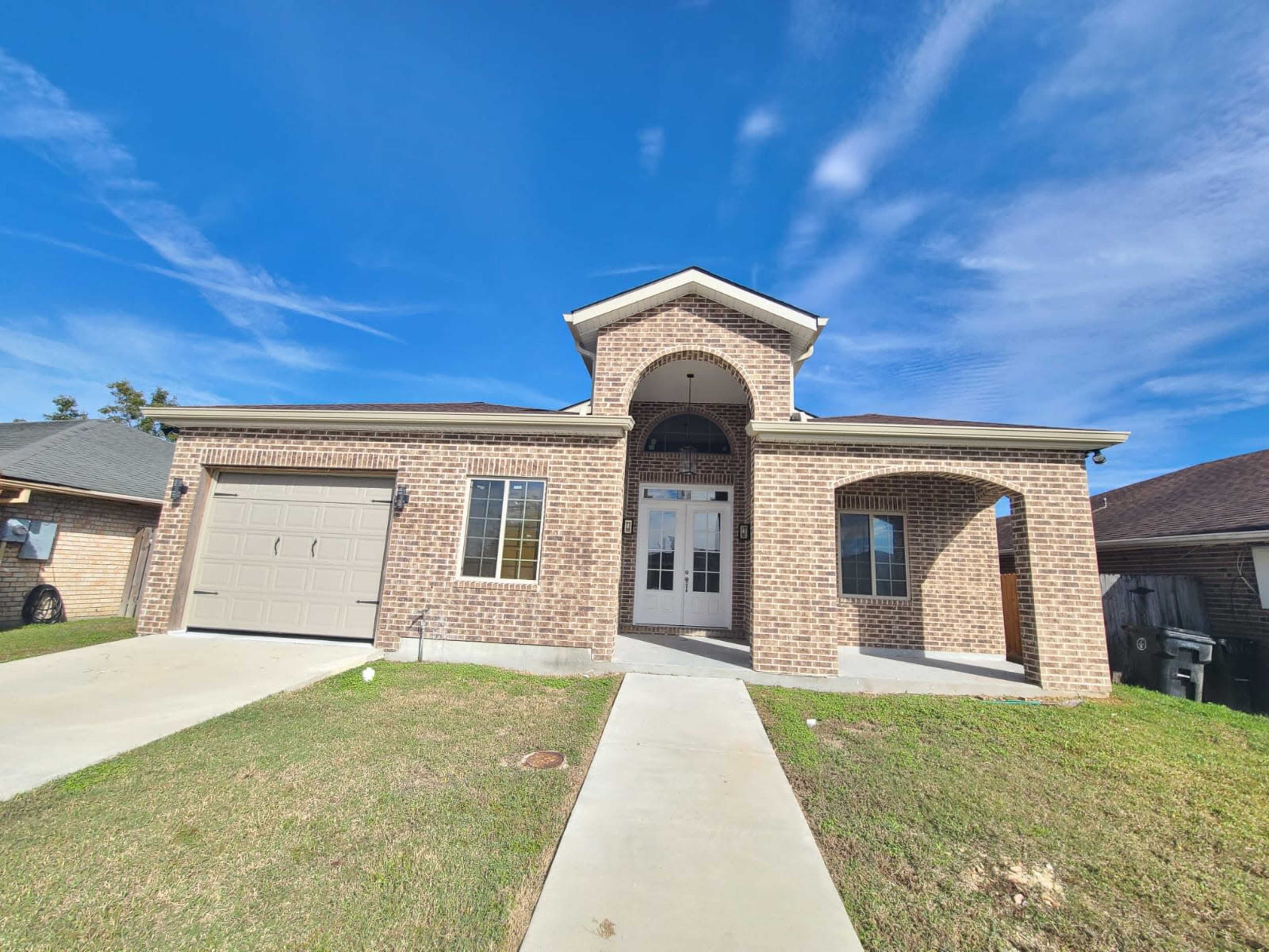 A single-story brick house with a front porch and a double-car garage.