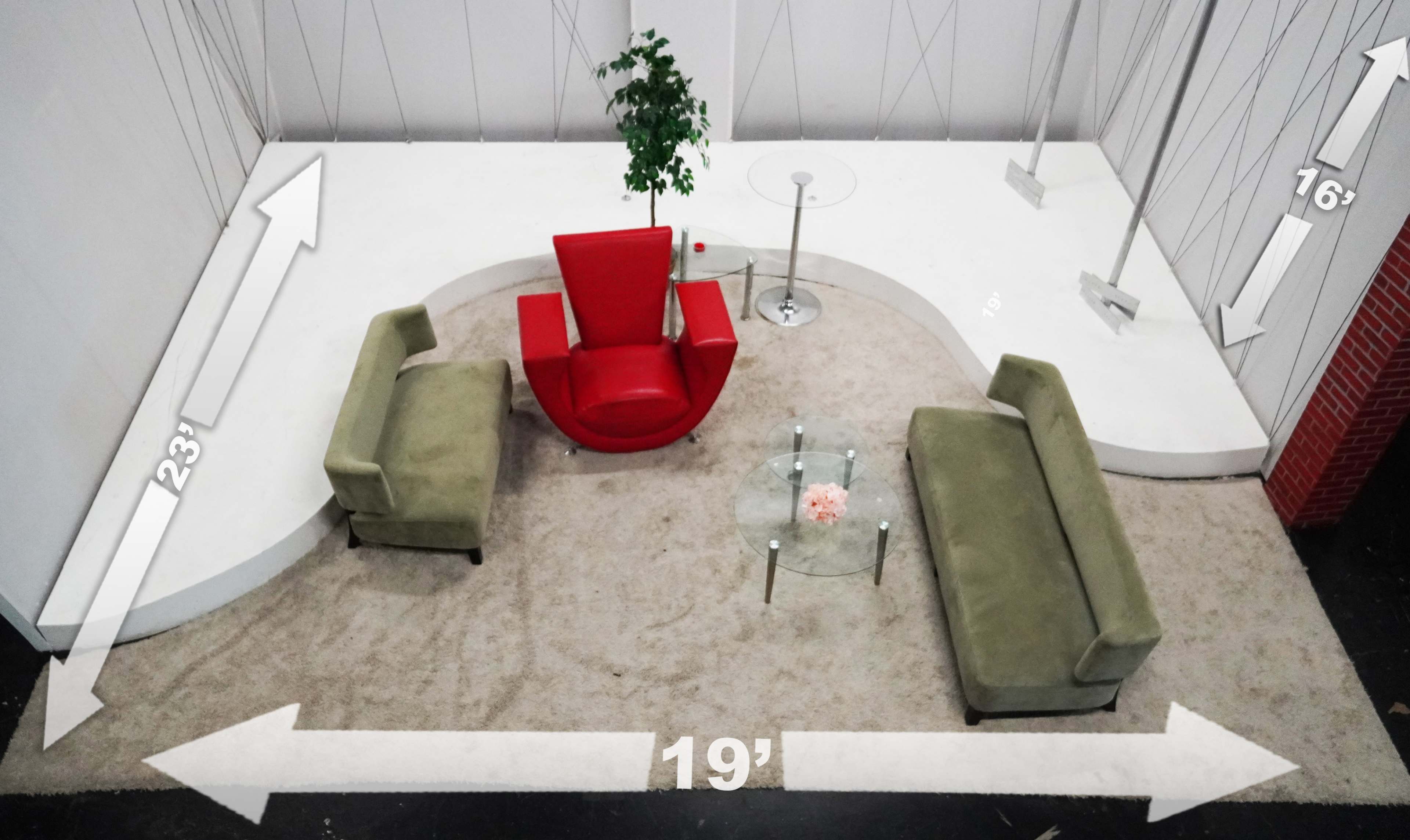 The image shows a modern seating arrangement featuring a red chair and two green couches on a white, curved platform with measurements indicated.