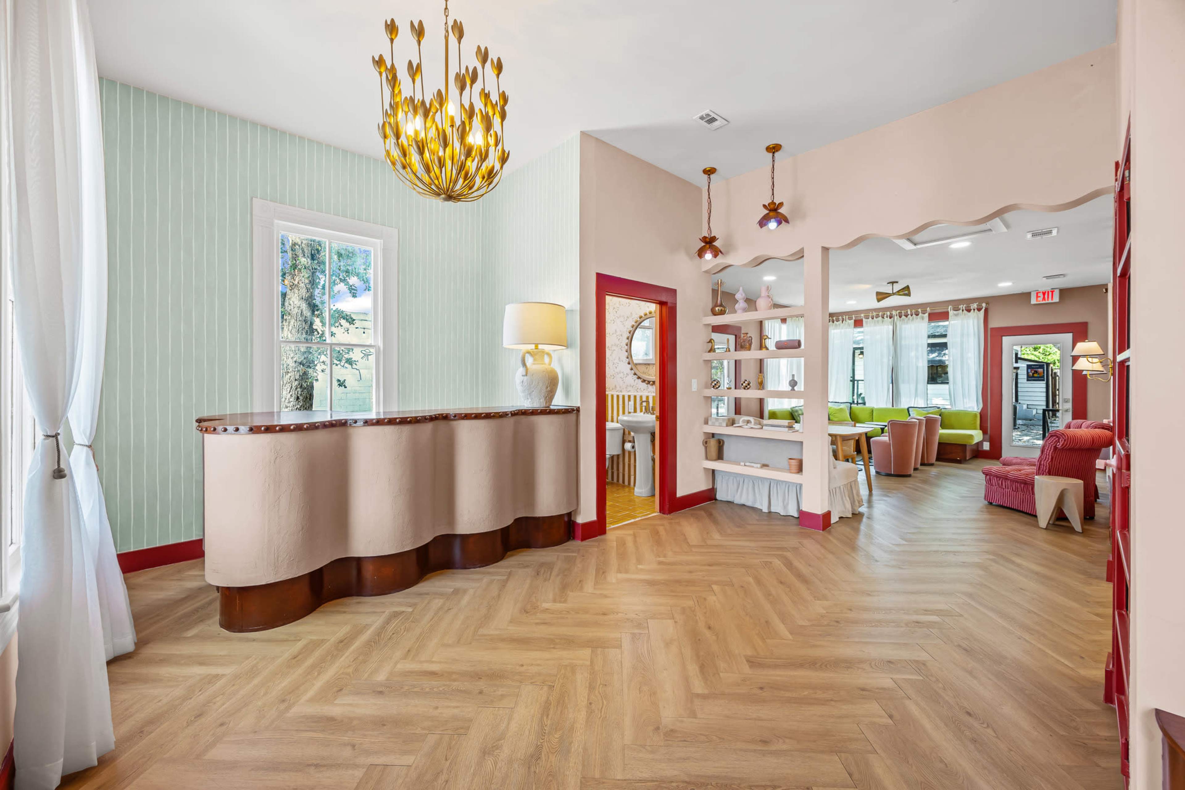 The image shows a brightly lit reception area with a curved wood desk and a casual seating area featuring colorful furniture.