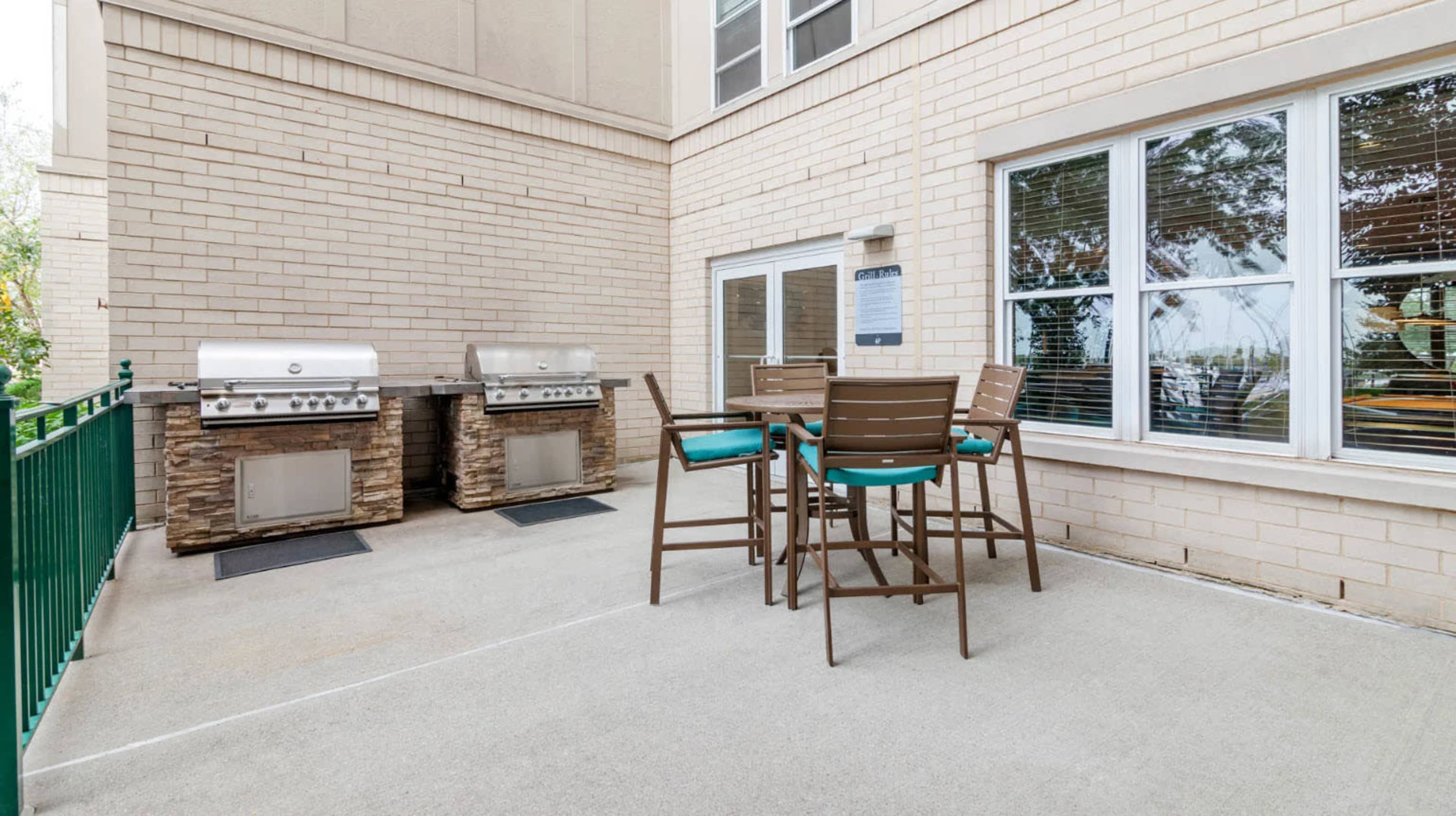 A patio area featuring two gas grills and a dining set with high chairs.