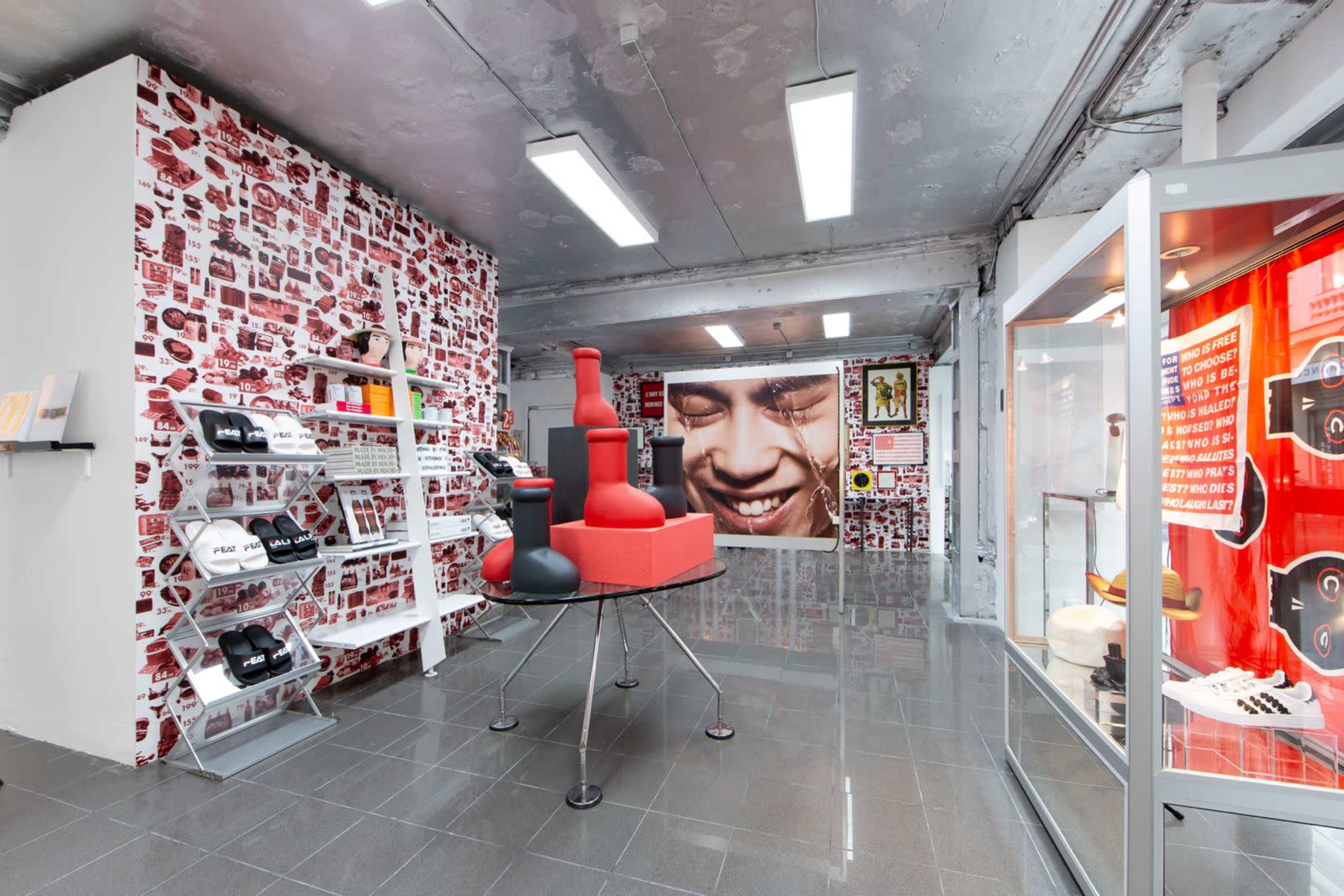 The image shows a modern retail space featuring red and white patterned walls, shelves displaying various products, and a central display with large red boxing gloves.
