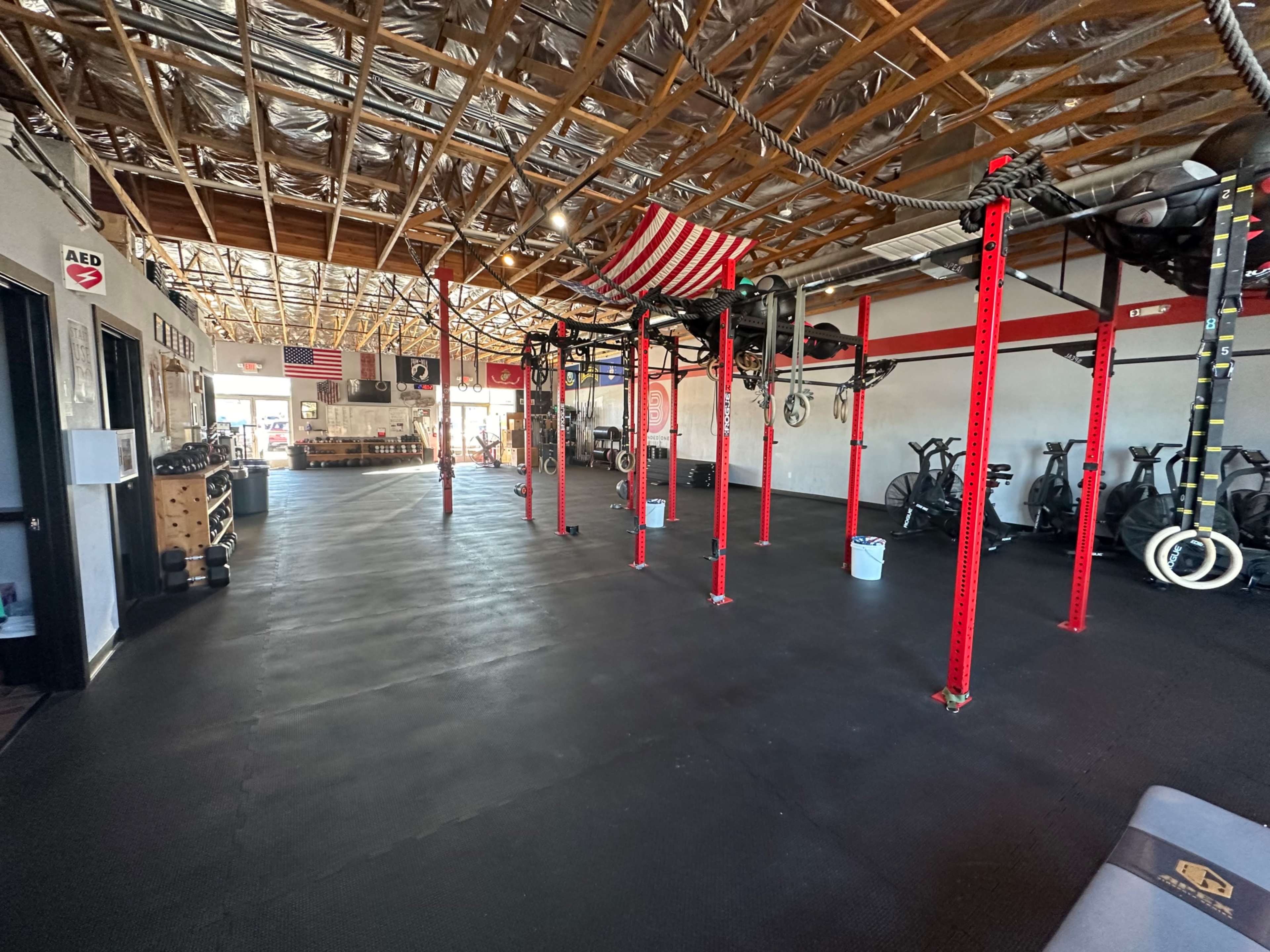 The interior of a gym with red support beams, exercise equipment, and an open floor space.