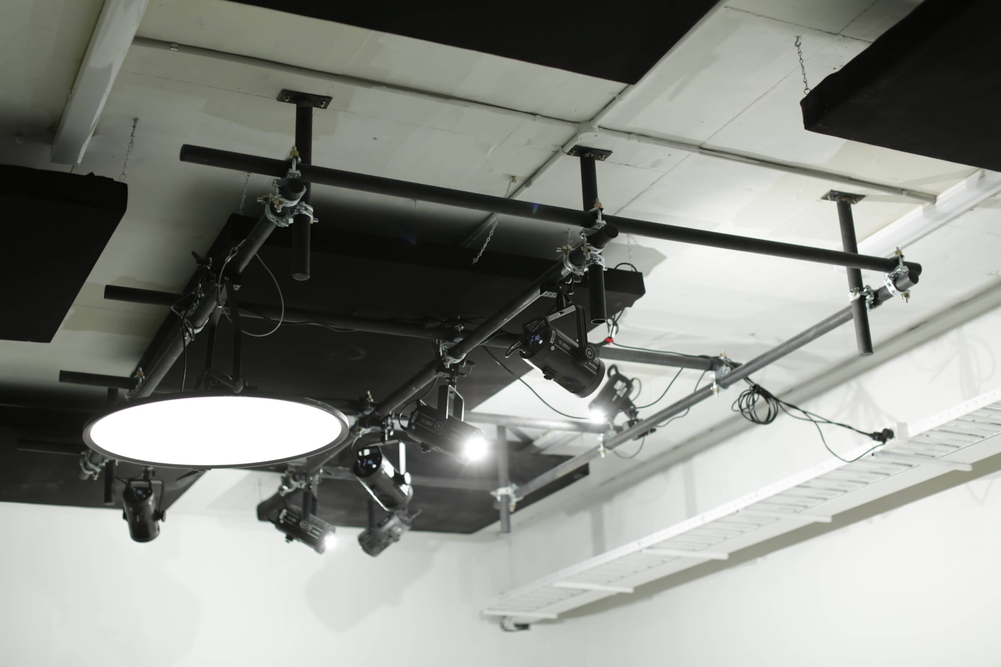 The image shows a grid of lighting equipment mounted on the ceiling, featuring various types of lights and a large circular light.