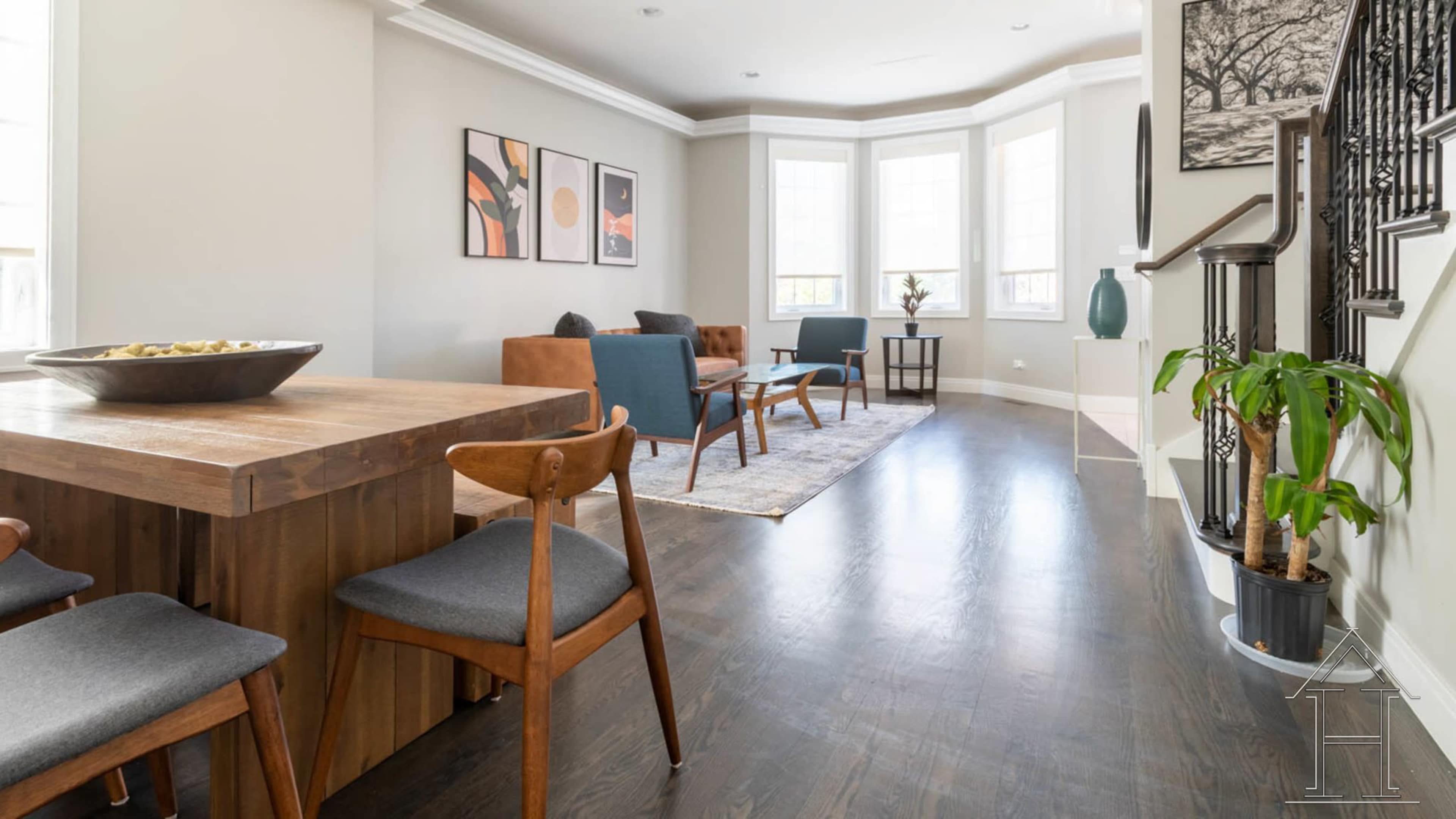 A modern living space with a dining table, seating area, and large windows allowing natural light.