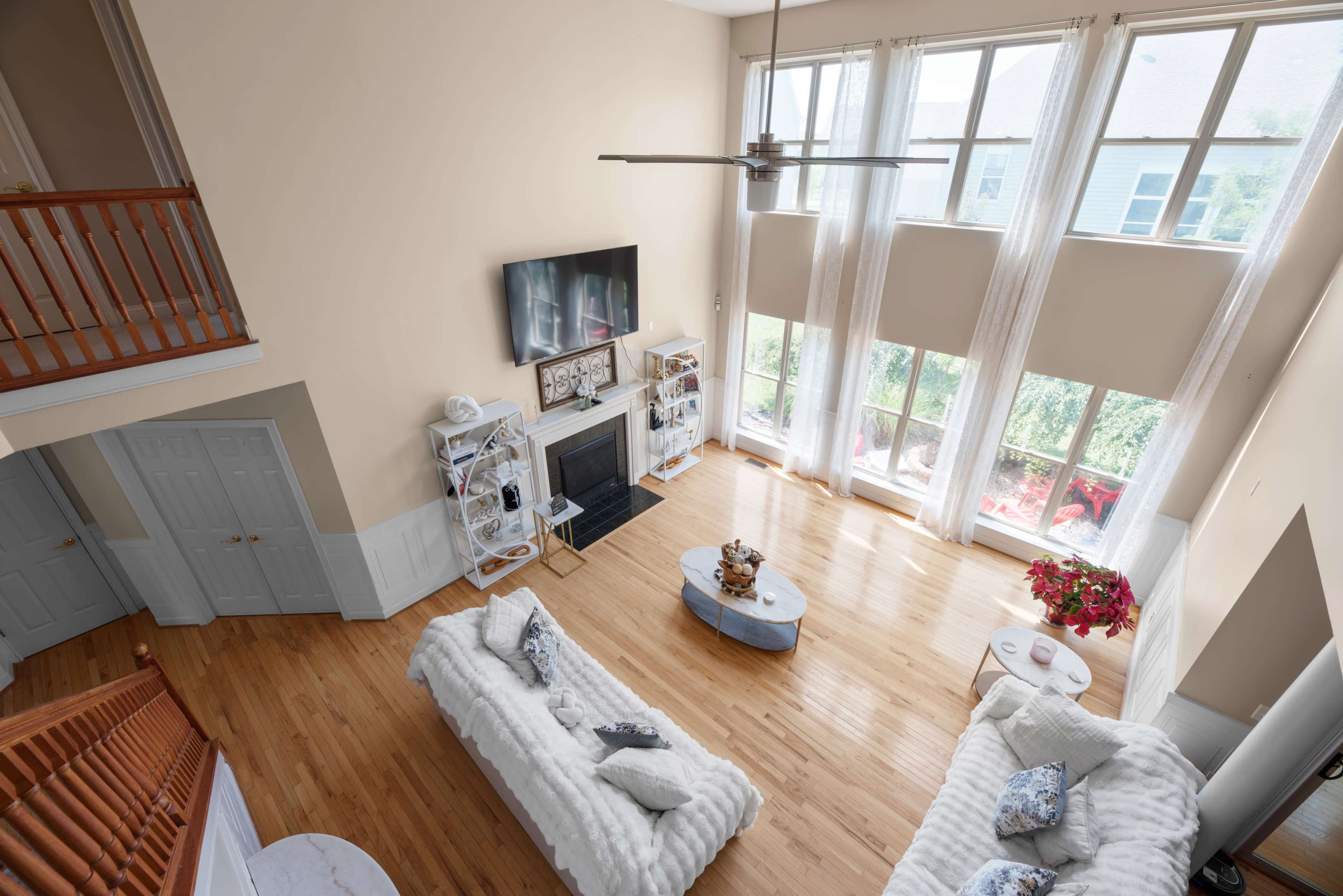 A spacious living room features two couches facing a coffee table, with large windows allowing natural light to illuminate the hardwood floor.