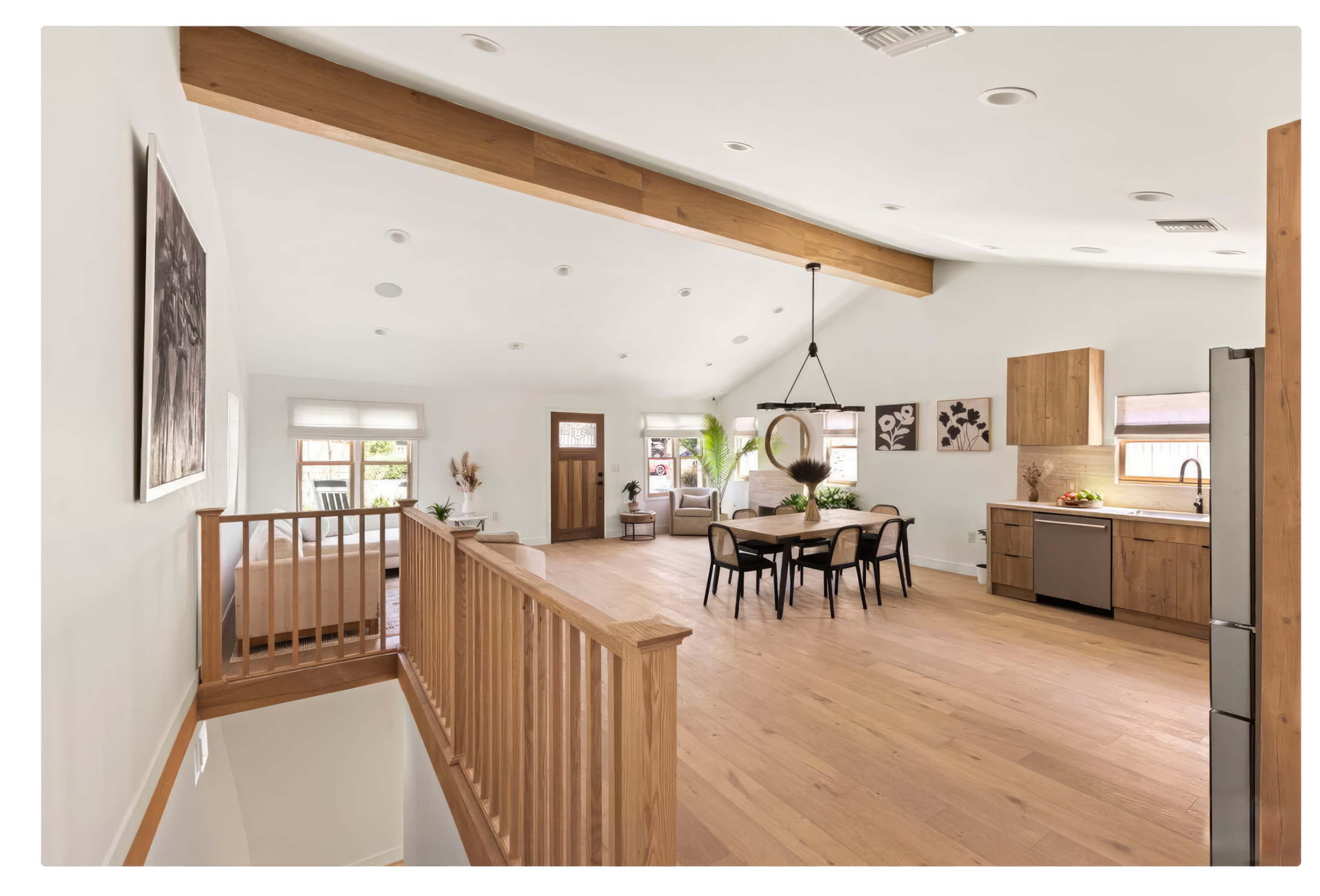 A spacious, modern living area featuring a kitchen, dining space, and a staircase leading to an upper level.