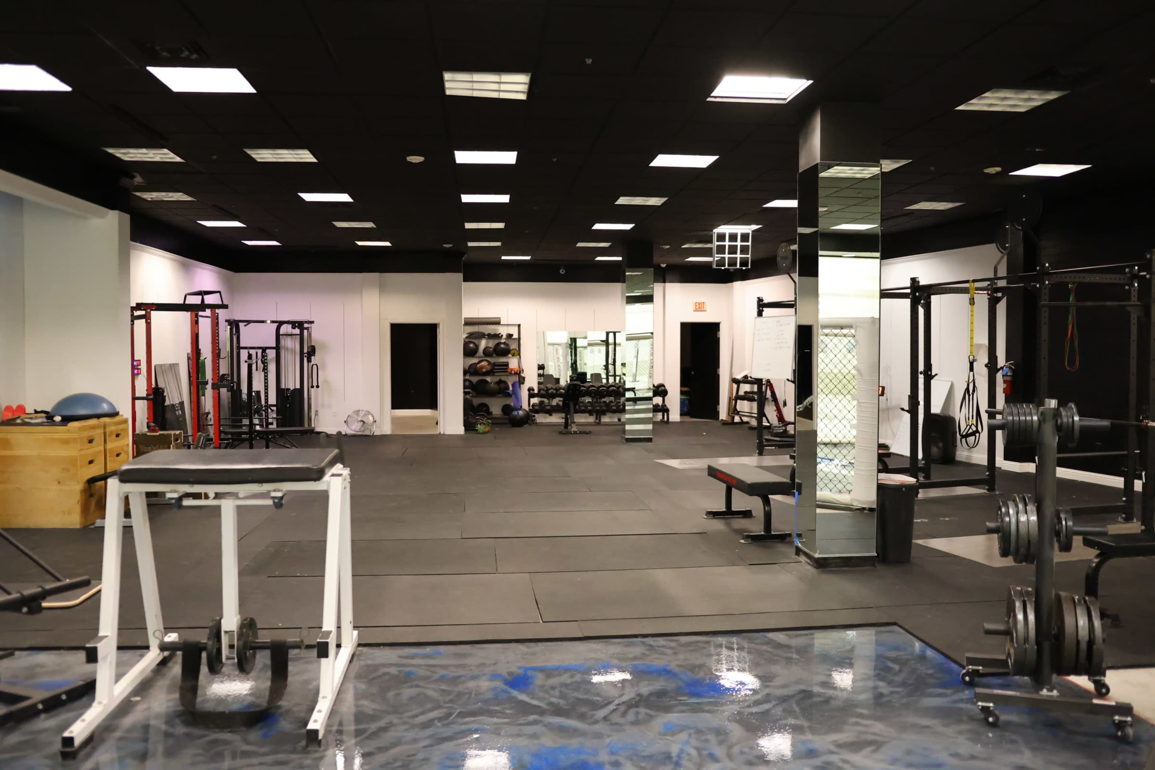 A spacious gym interior equipped with various weightlifting and fitness equipment, including benches and racks.