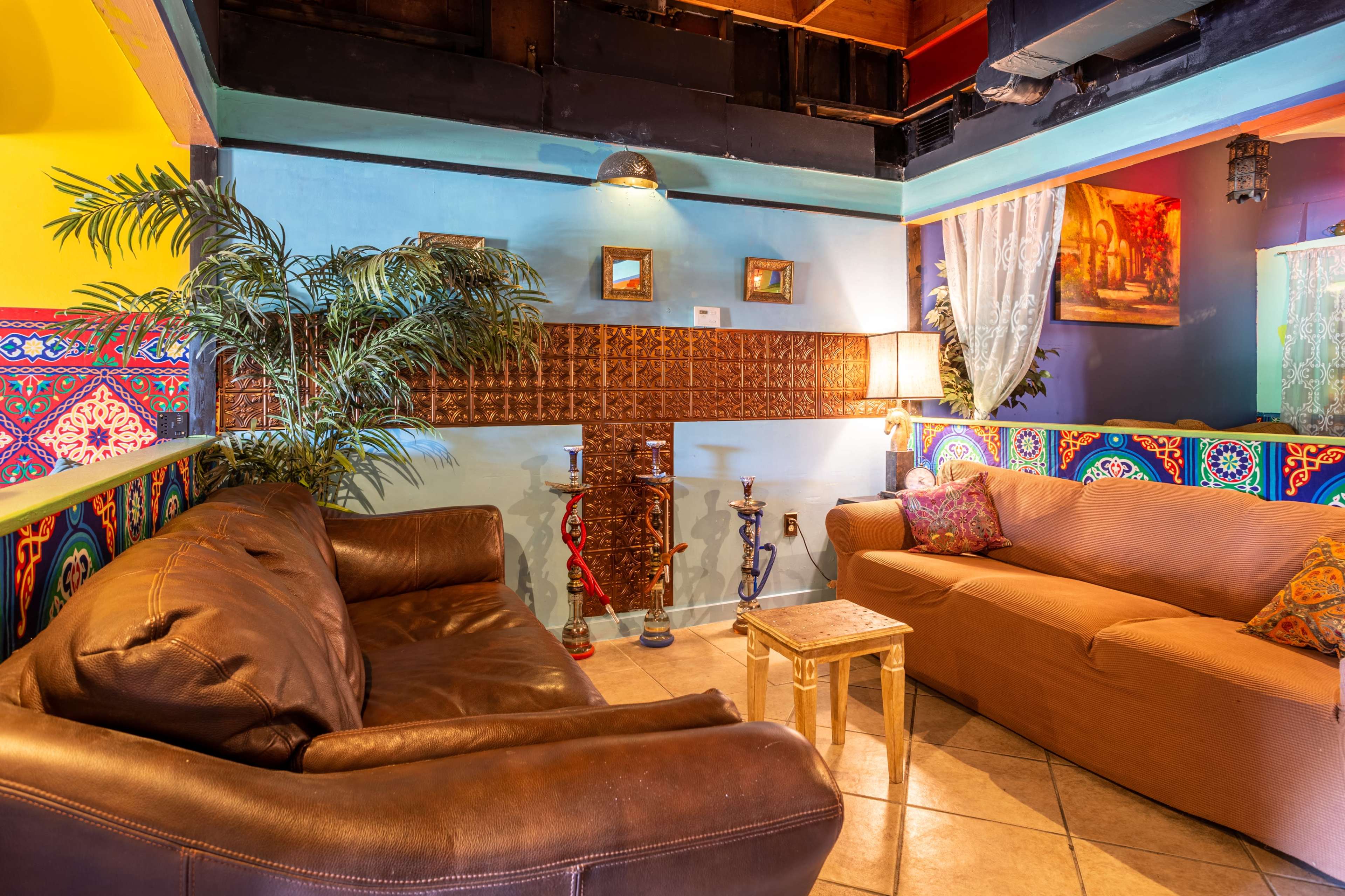 A cozy seating area with two sofas, a small table, and decorative walls featuring vibrant colors and patterns.