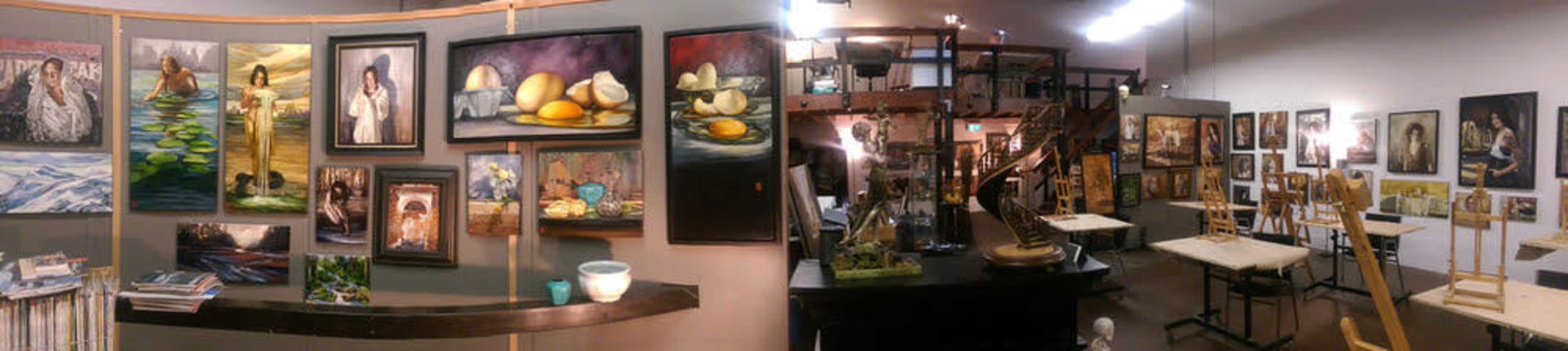 An art gallery featuring a variety of paintings displayed on walls, with artists' workstations and supplies visible in the background.