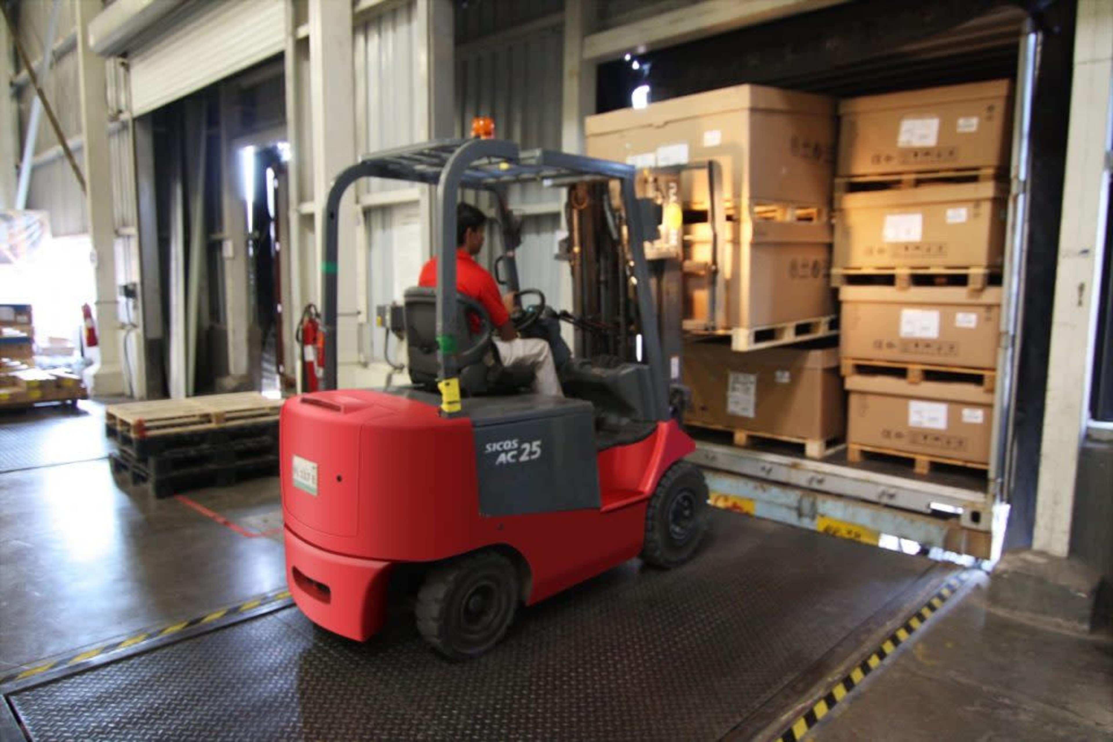 A forklift is unloading boxes from a truck at a loading dock.