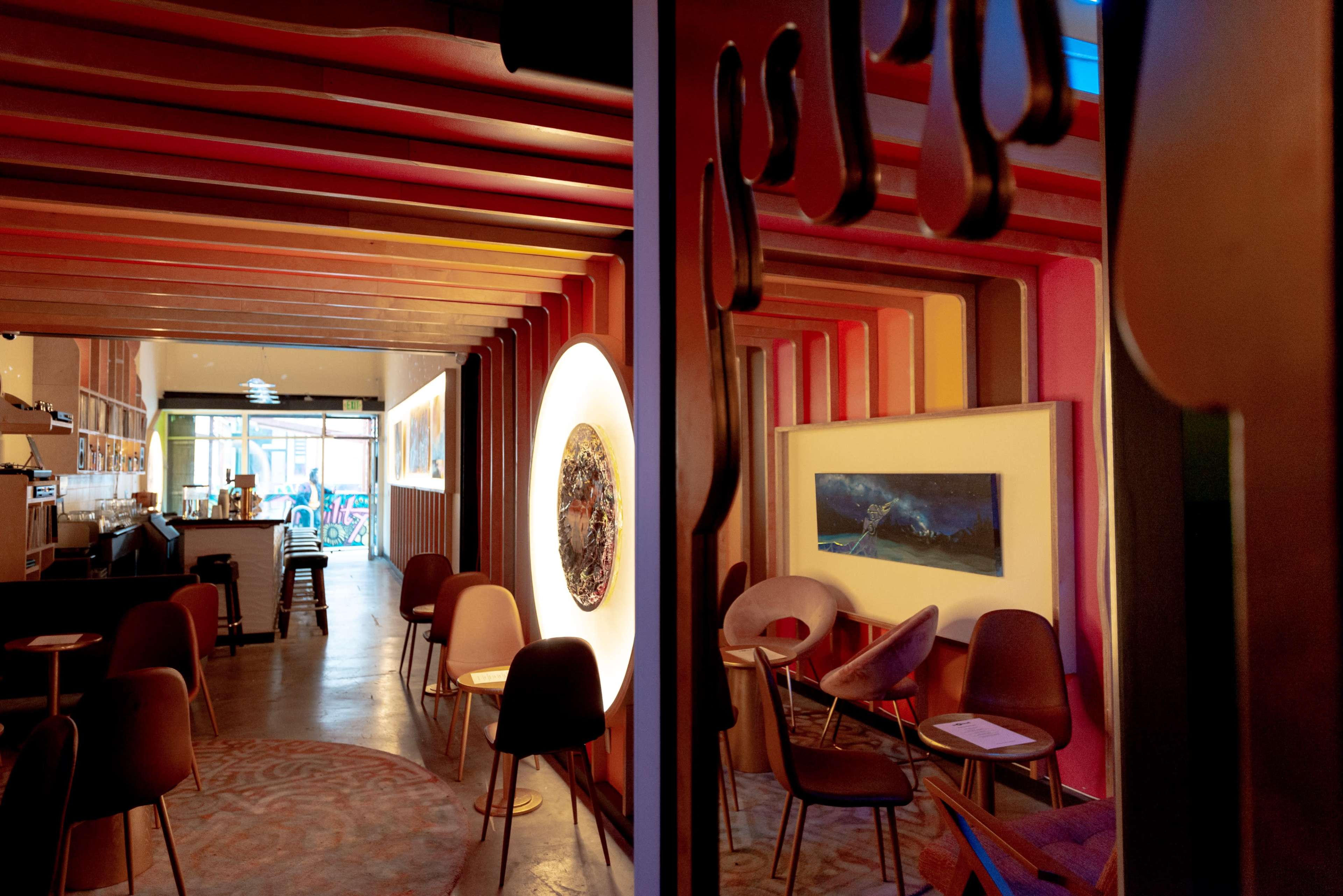 A modern café interior with vibrant wall colors, artistic decorations, and seating areas.