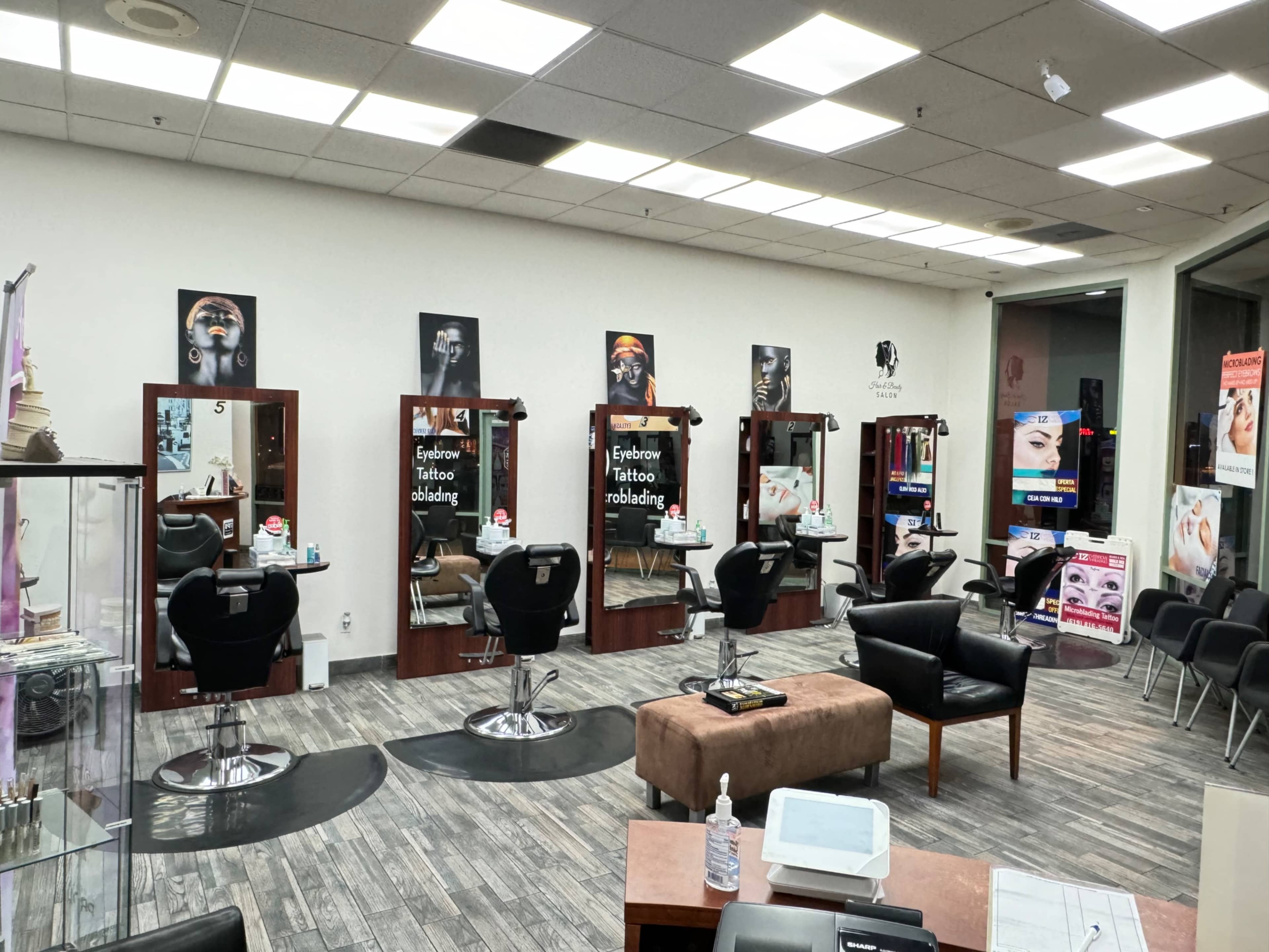 The image shows a beauty salon with several styling stations, each equipped with mirrors and salon chairs, alongside promotional posters on the walls.