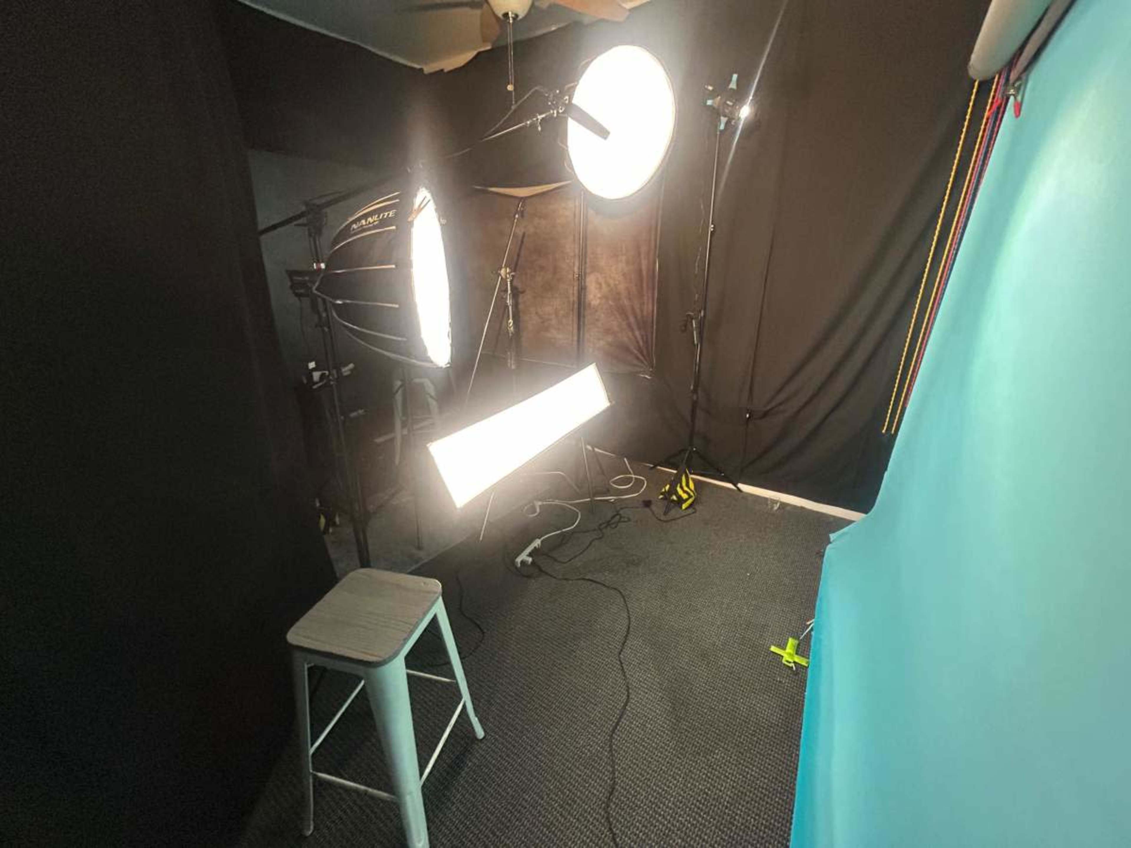 The image shows a small photo studio set up with multiple lighting fixtures and a blue backdrop.