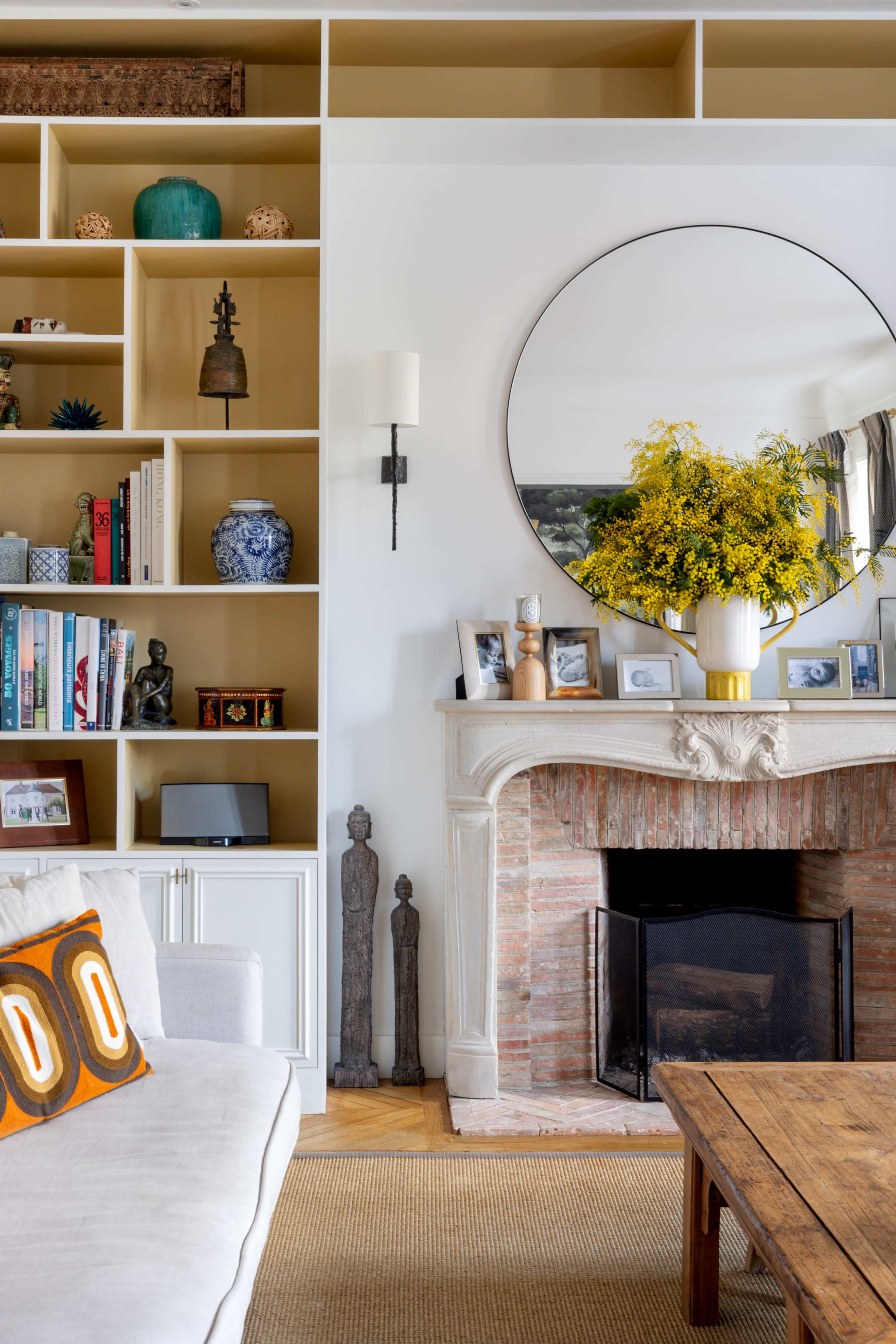 A well-designed living room features a white sofa, a wooden coffee table, and a stylish fireplace surrounded by shelves filled with decorative items and books.