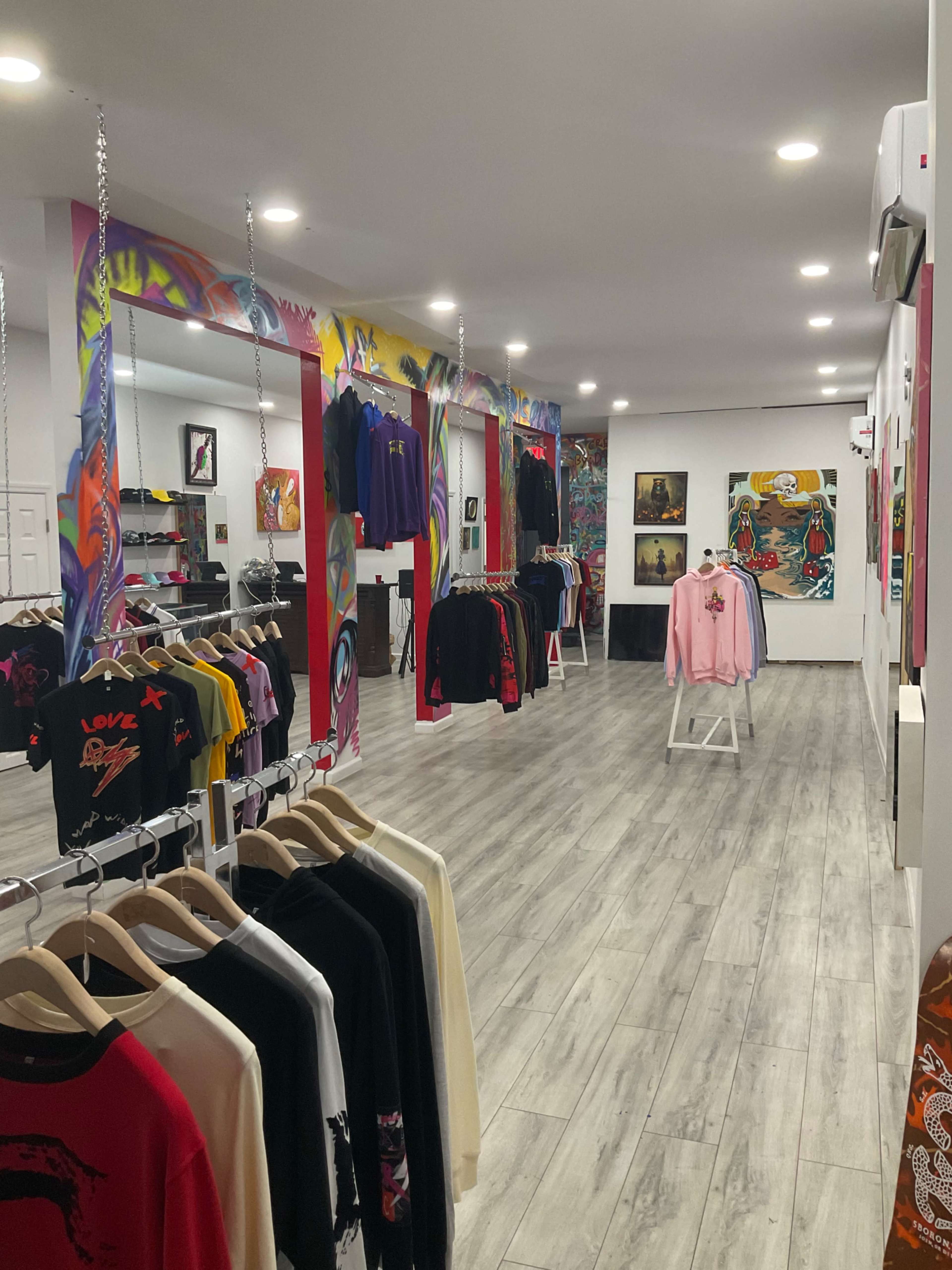 A clothing store interior with colorful walls and various apparel displayed on racks and hangers.