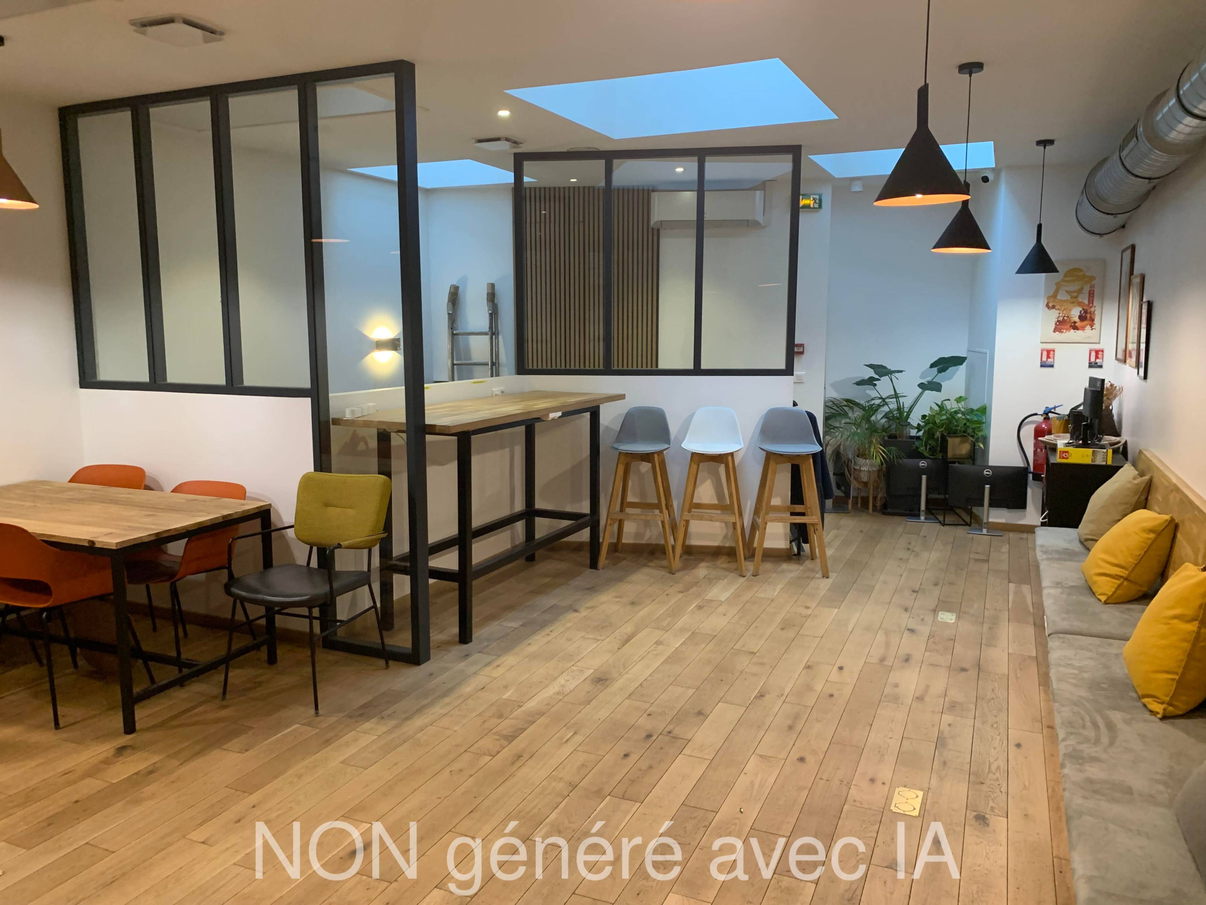 The image depicts a modern interior space with wooden flooring, a seating area featuring tables and chairs, and a partitioned section with bar stools and a counter.