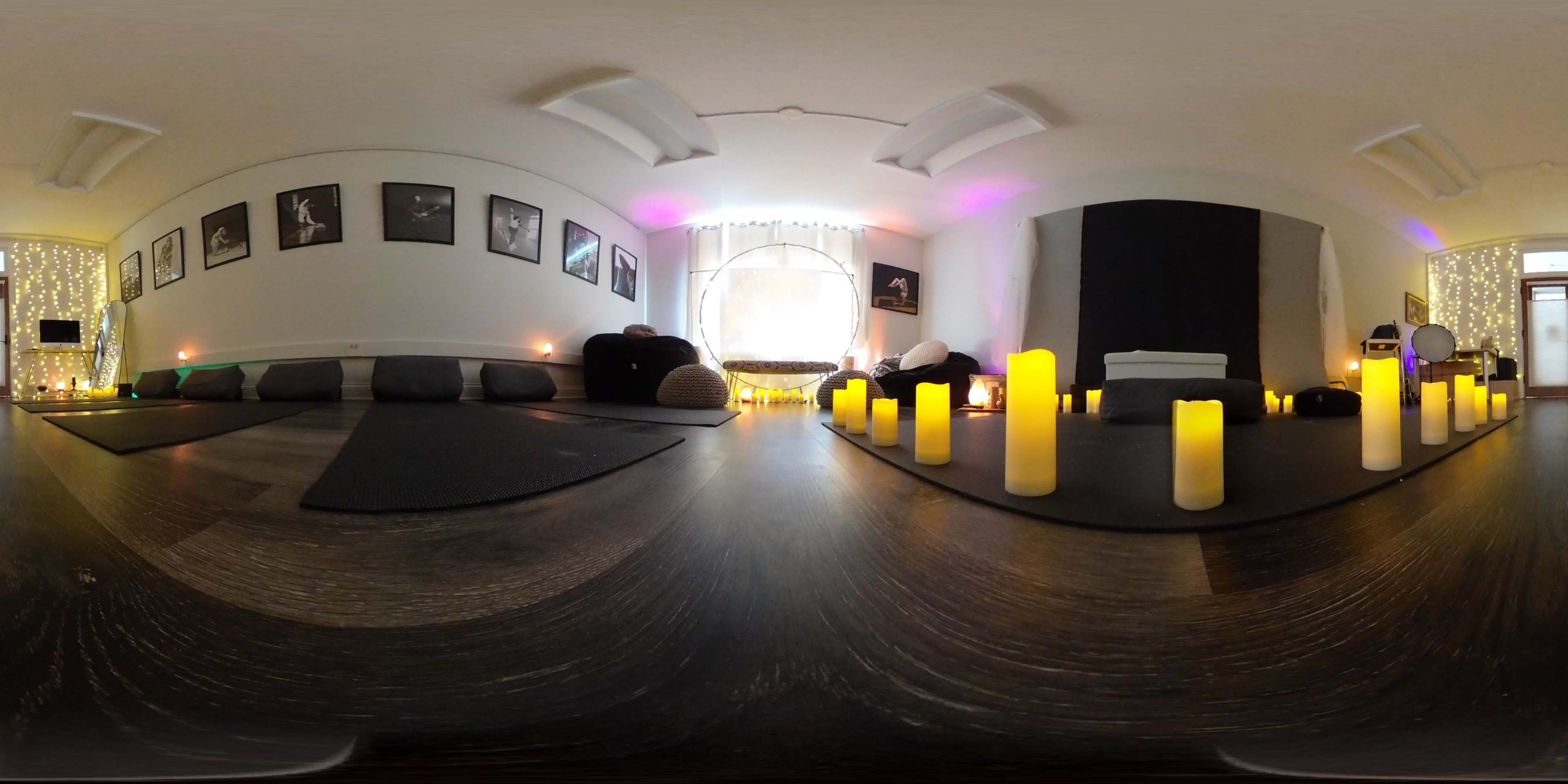 The image shows a calm, dimly lit room with yoga mats, candles, and art on the walls, creating a serene atmosphere.