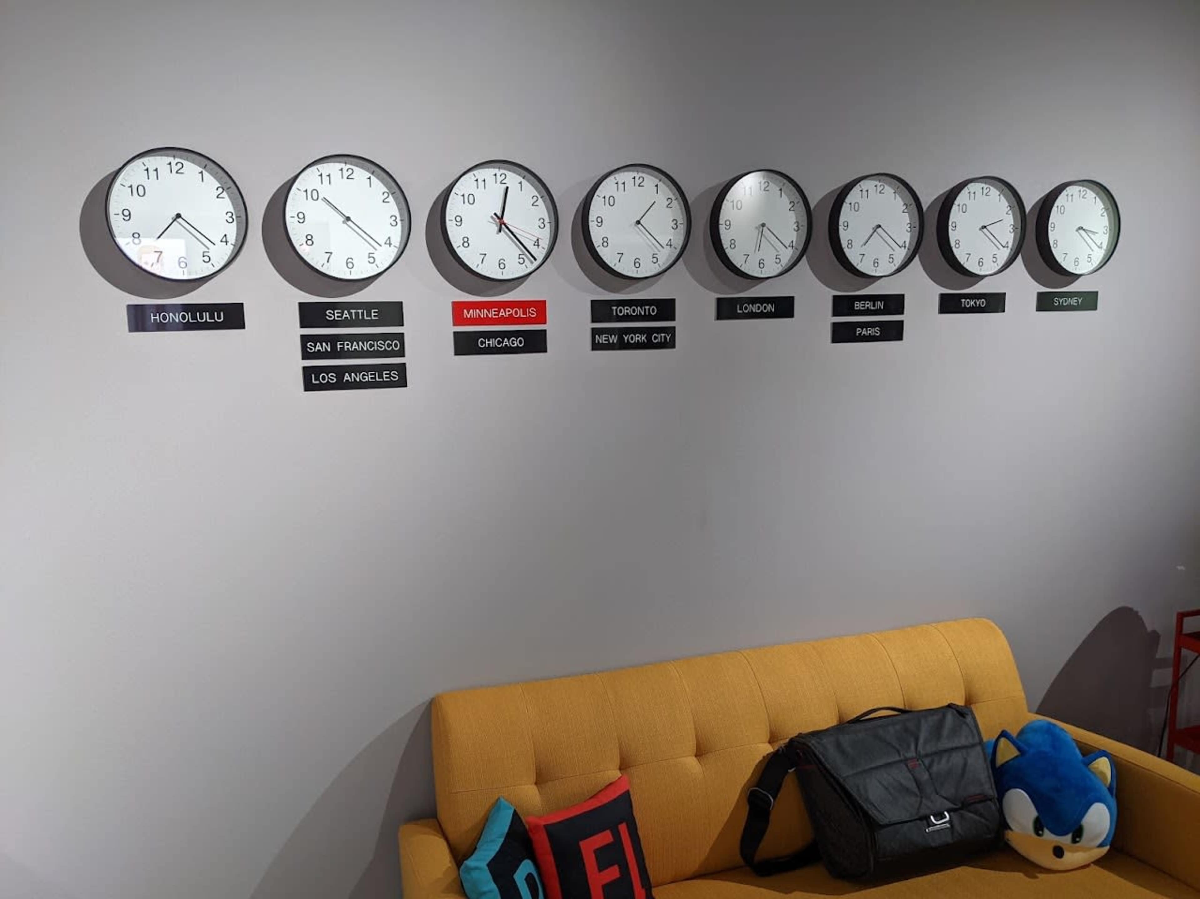 A wall displays eight clocks showing different times for various cities, accompanied by city labels beneath each clock.