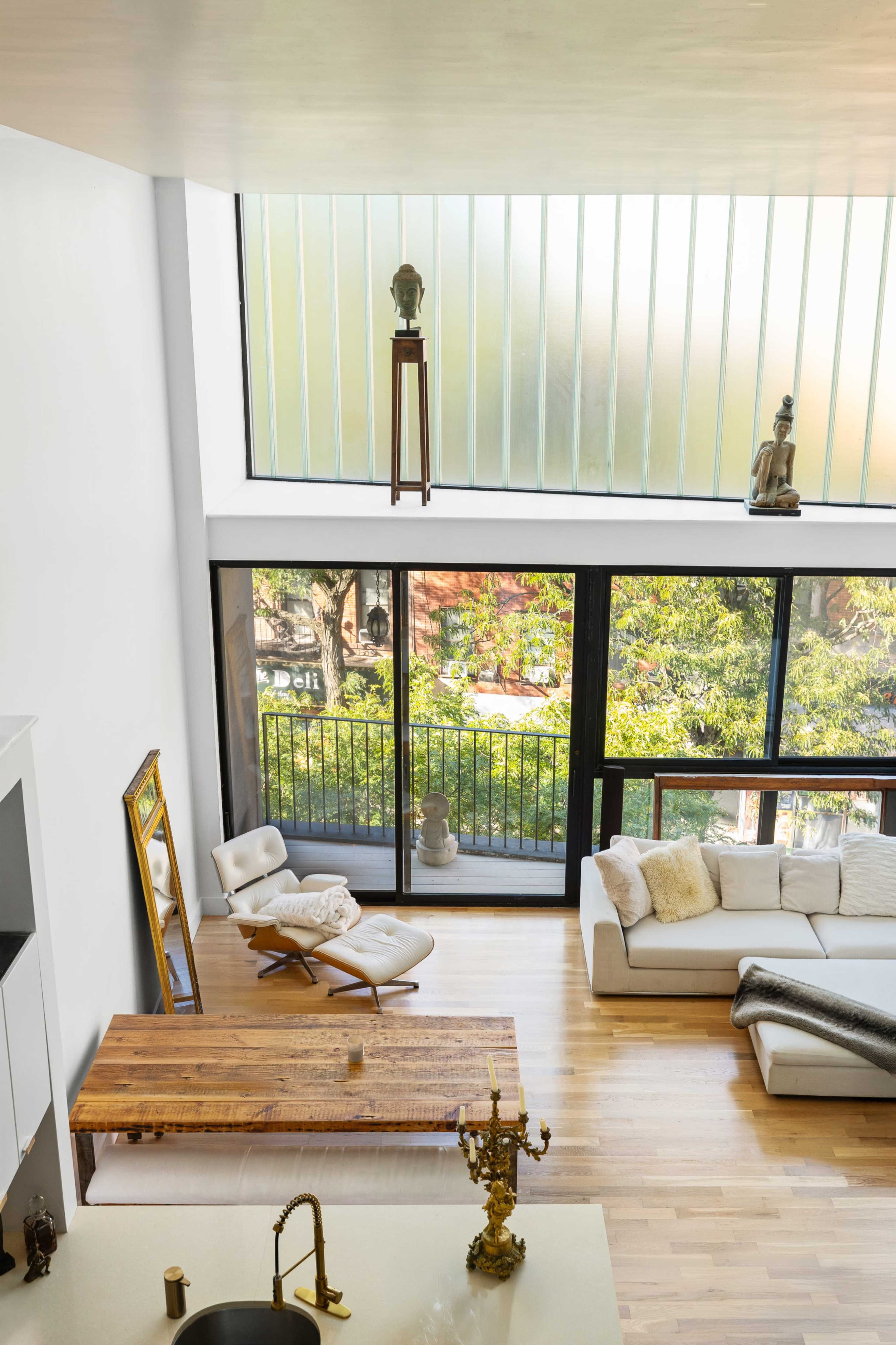 A modern living space features a large window overlooking a garden, minimalistic furniture, and a wooden coffee table.