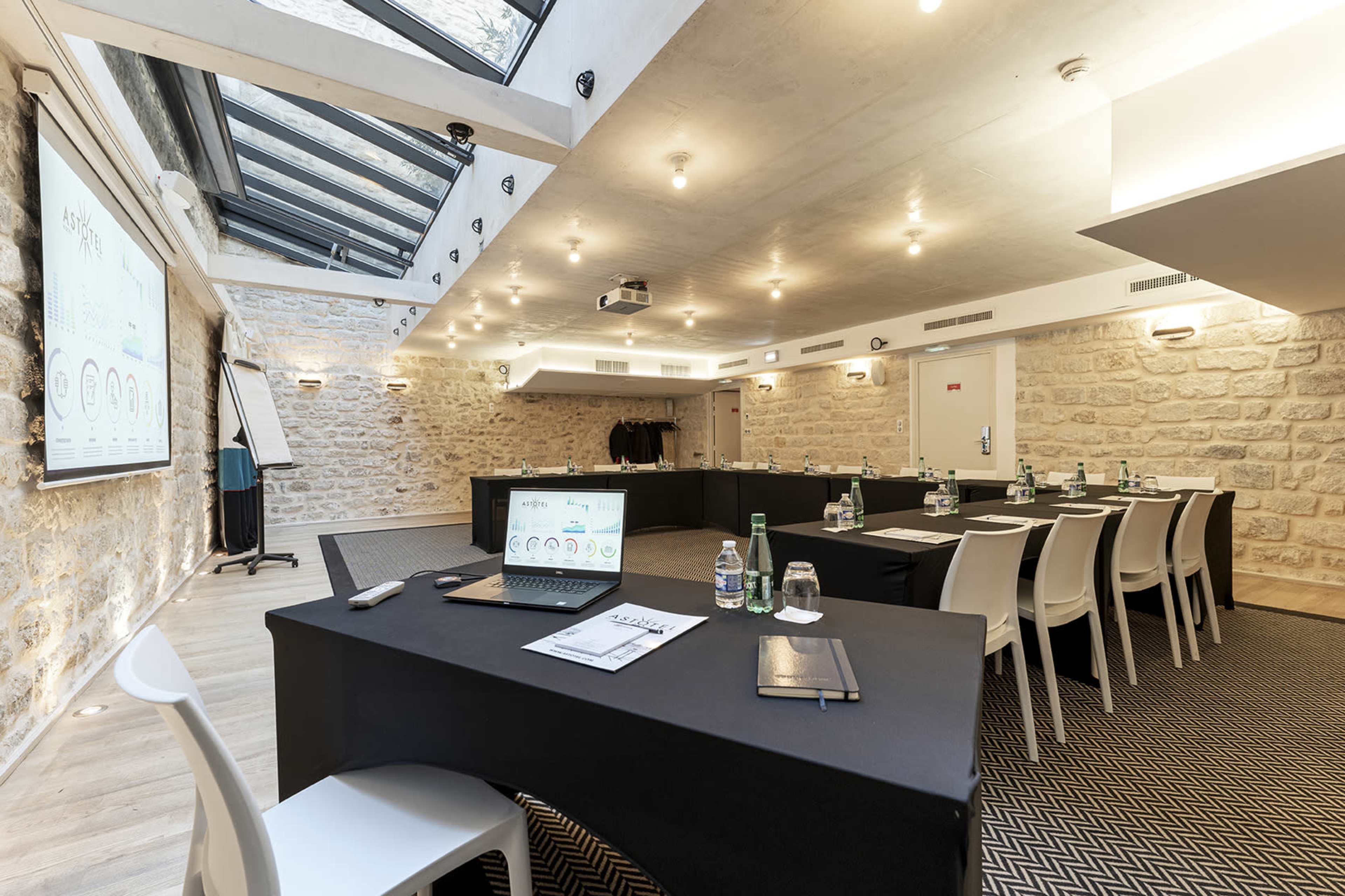 A modern conference room with a long table, chairs, and a large skylight illuminating the space.