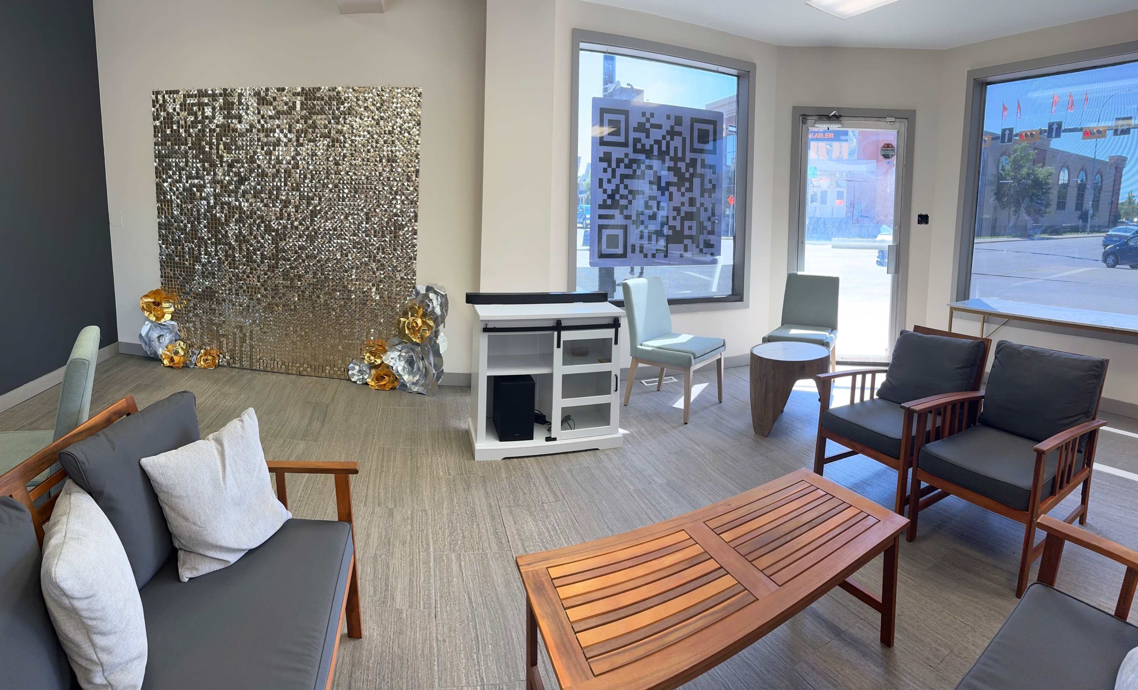 A modern waiting area with wooden furniture, a metallic decorative wall, and a large QR code displayed near the entrance.